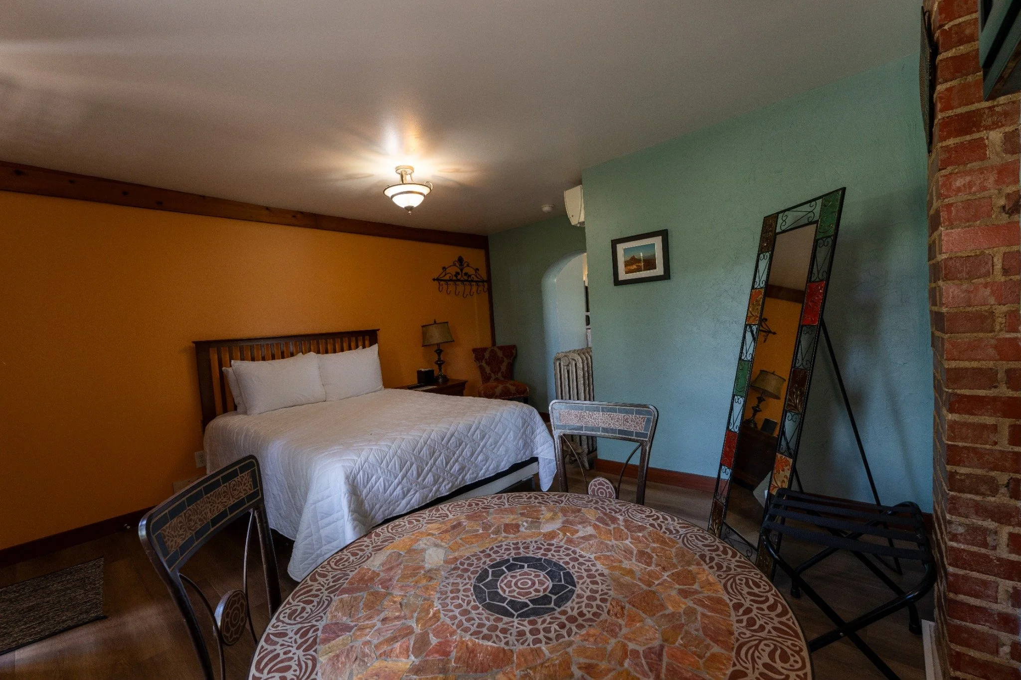 Cozy Wagon Wheel Motel guest room with original hardwood floors, exposed stone and brick, and a mosaic table.