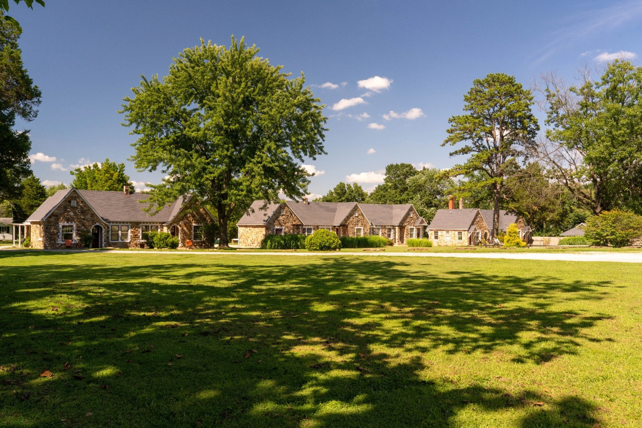 Wide daytime view across the lawn toward the Wagon Wheel Motel’s historic stone guest cottages.