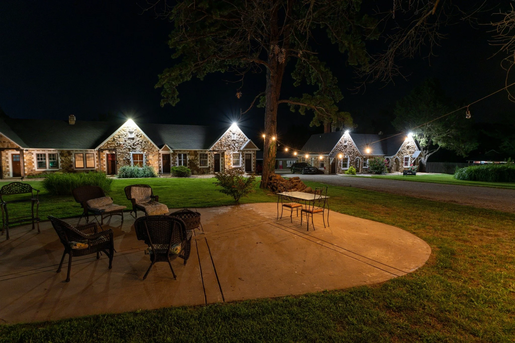 Outdoor guest patio and historic Wagon Wheel Motel stone cottages illuminated at night.