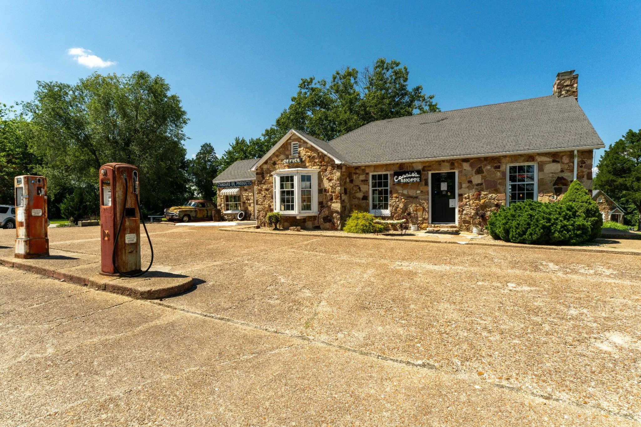 Daytime view of the Wagon Wheel Motel stone office and vintage gas pumps along Route 66.