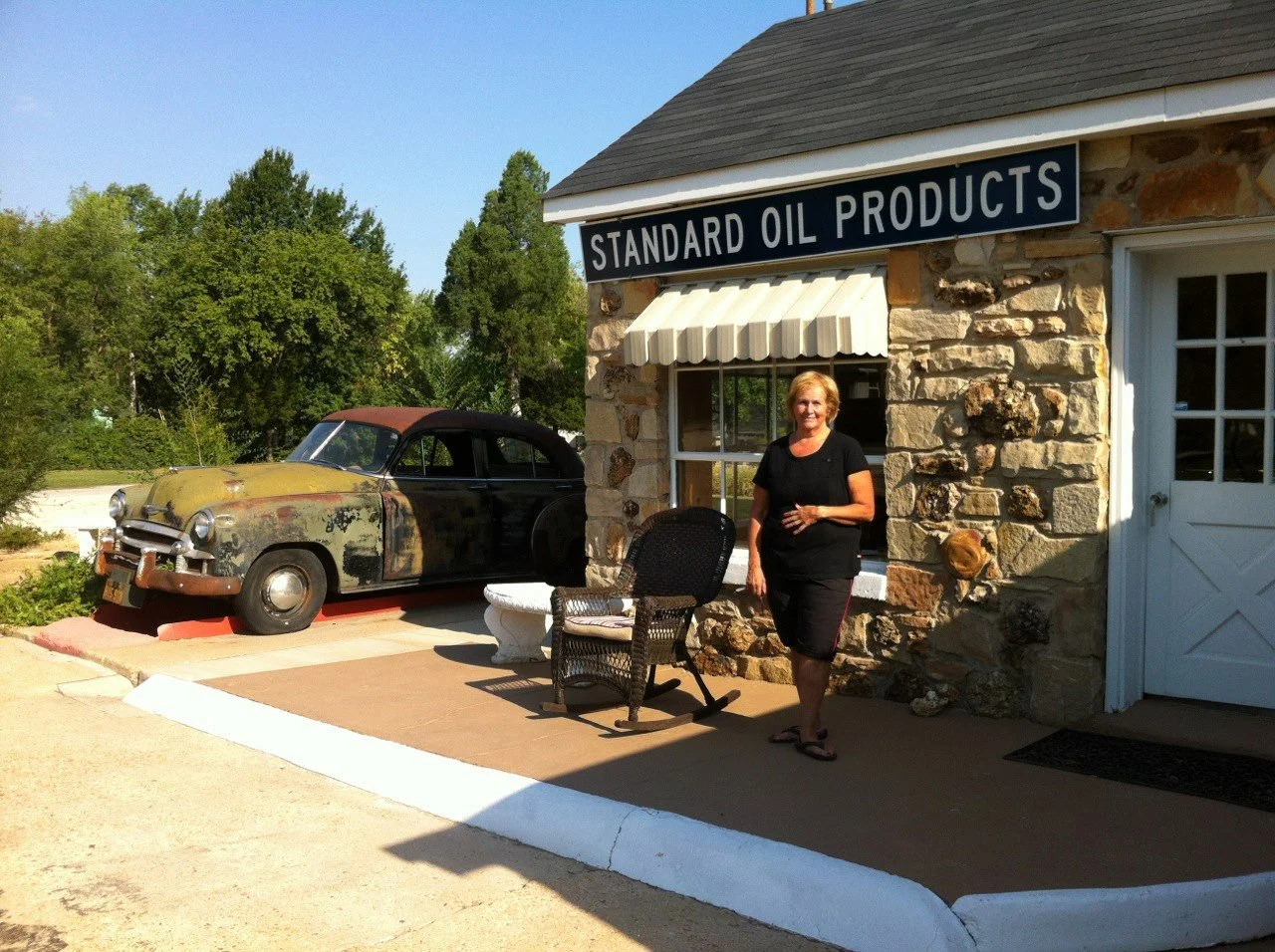 Connie Echols outside the Wagon Wheel Motel office beside a vintage automobile