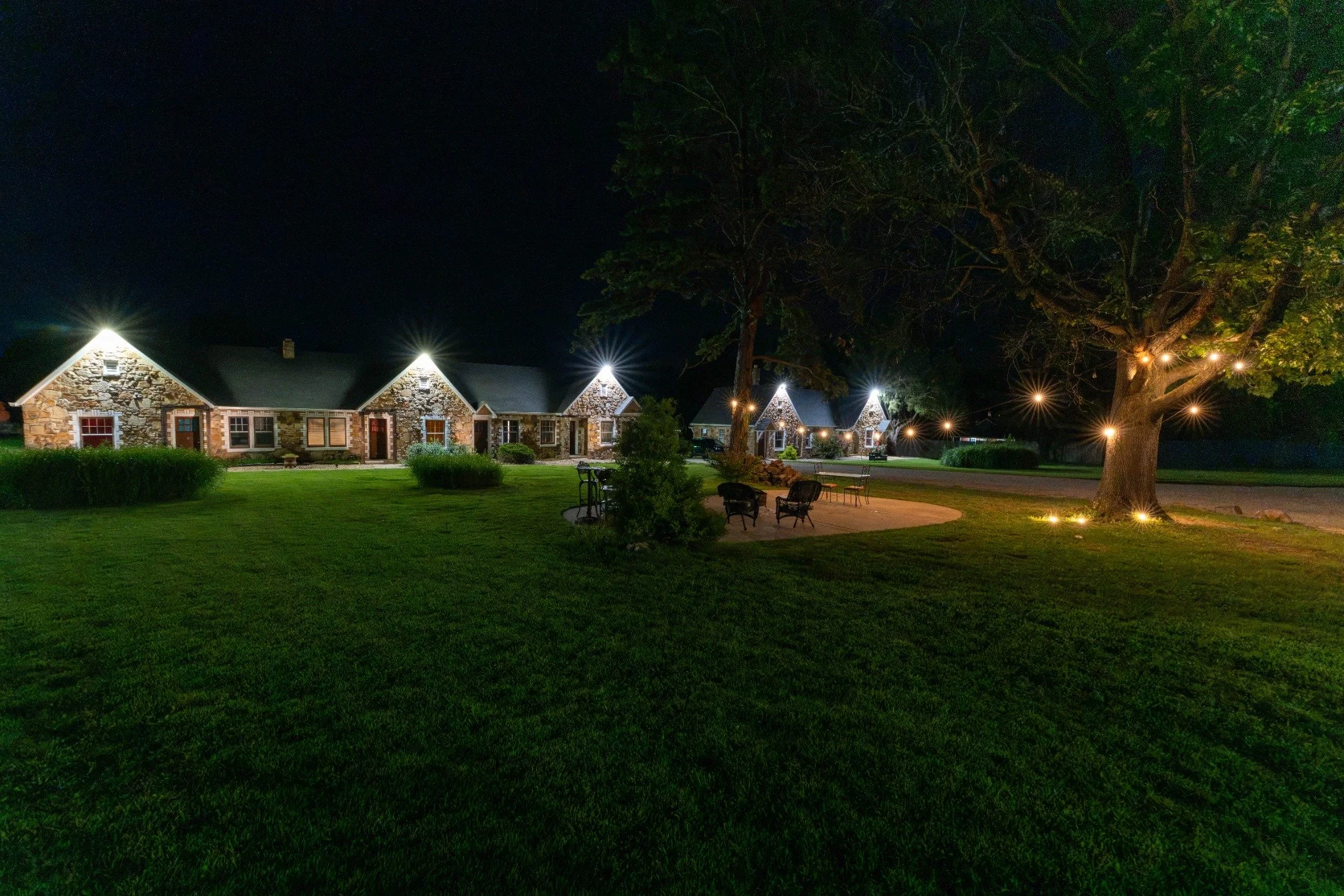 Night view across the Wagon Wheel Motel lawn toward the illuminated historic stone guest cottages.