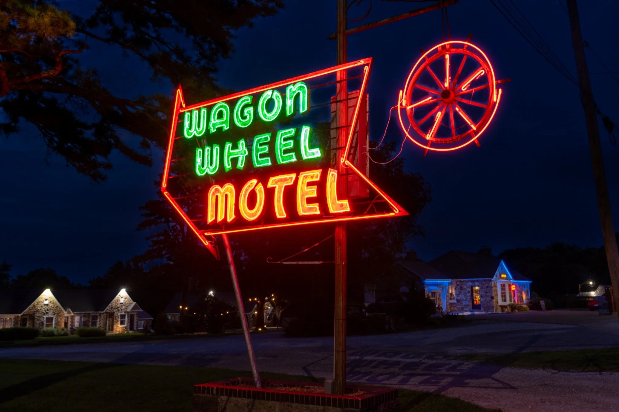 Wagon Wheel Motel neon sign and illuminated stone cottages beside historic Route 66 in Cuba, Missouri