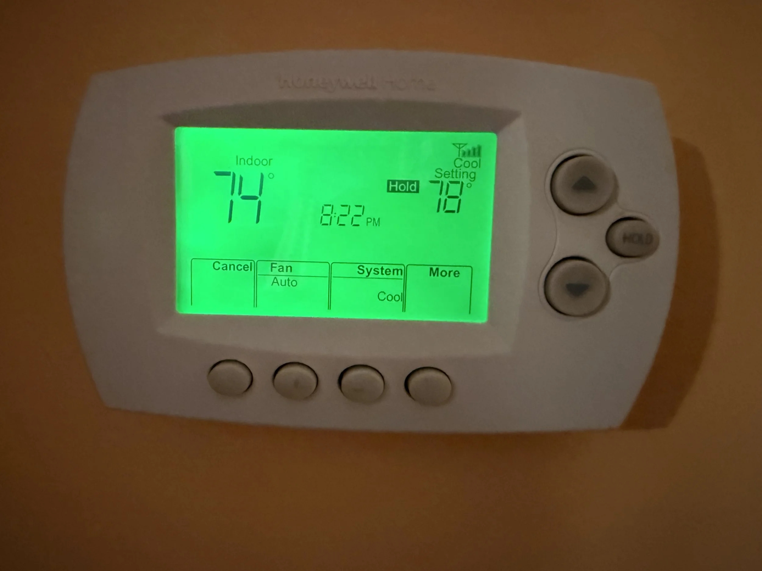 A digital thermostat displays the indoor temperature as 74°F and the outdoor temperature as 78°F, with a green backlit screen and several physical buttons on the right side.