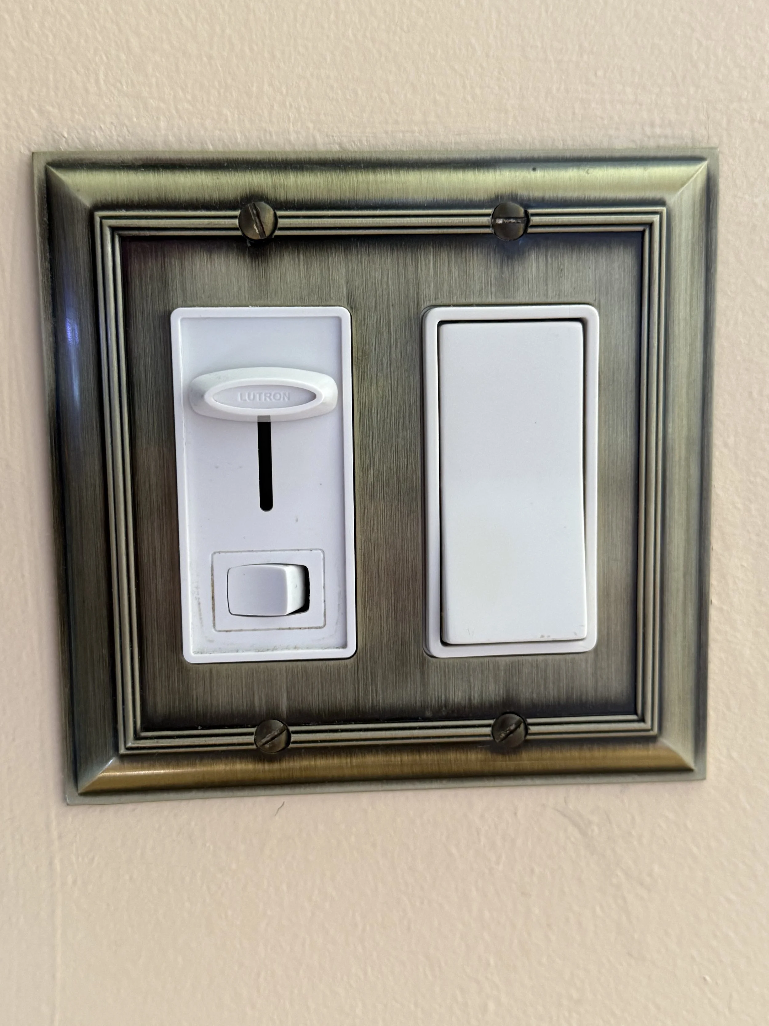 A metal wall plate with two switches and a GFCI outlet, mounted on a beige wall.