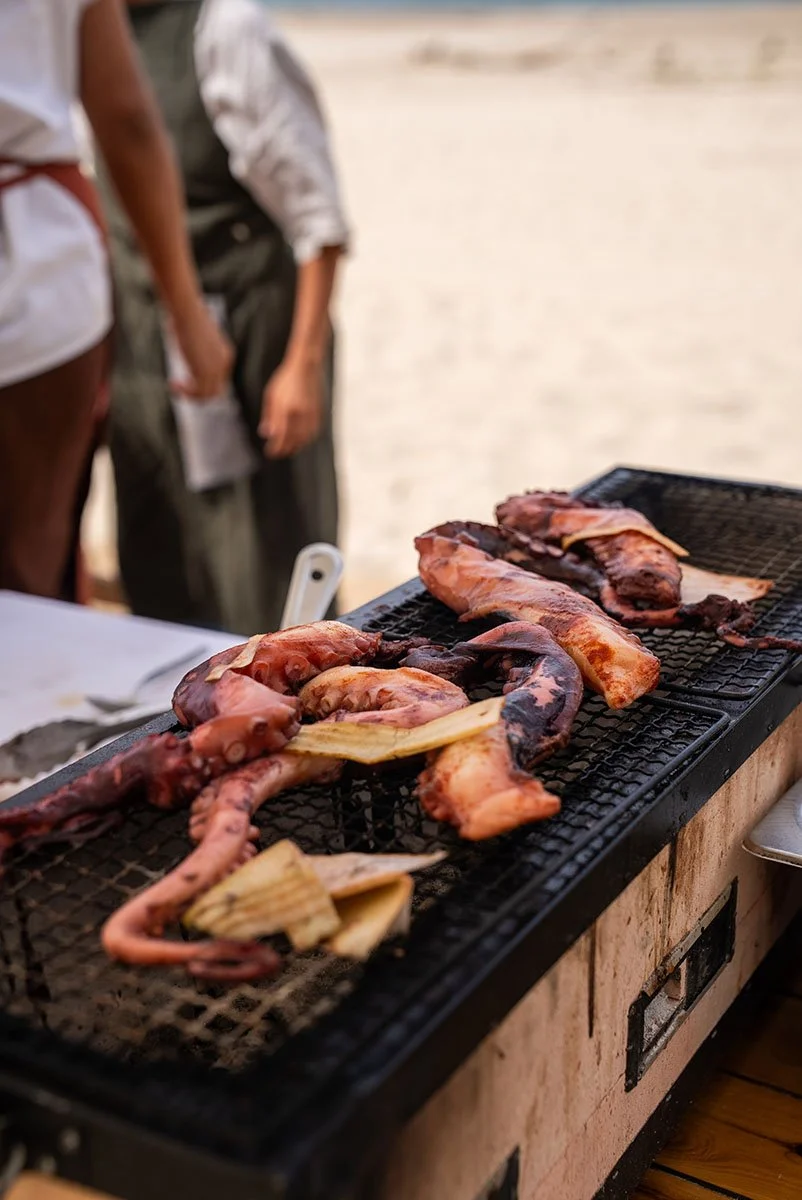 Octopus and bamboo shoots grilling on a barbecue grill outdoors.
