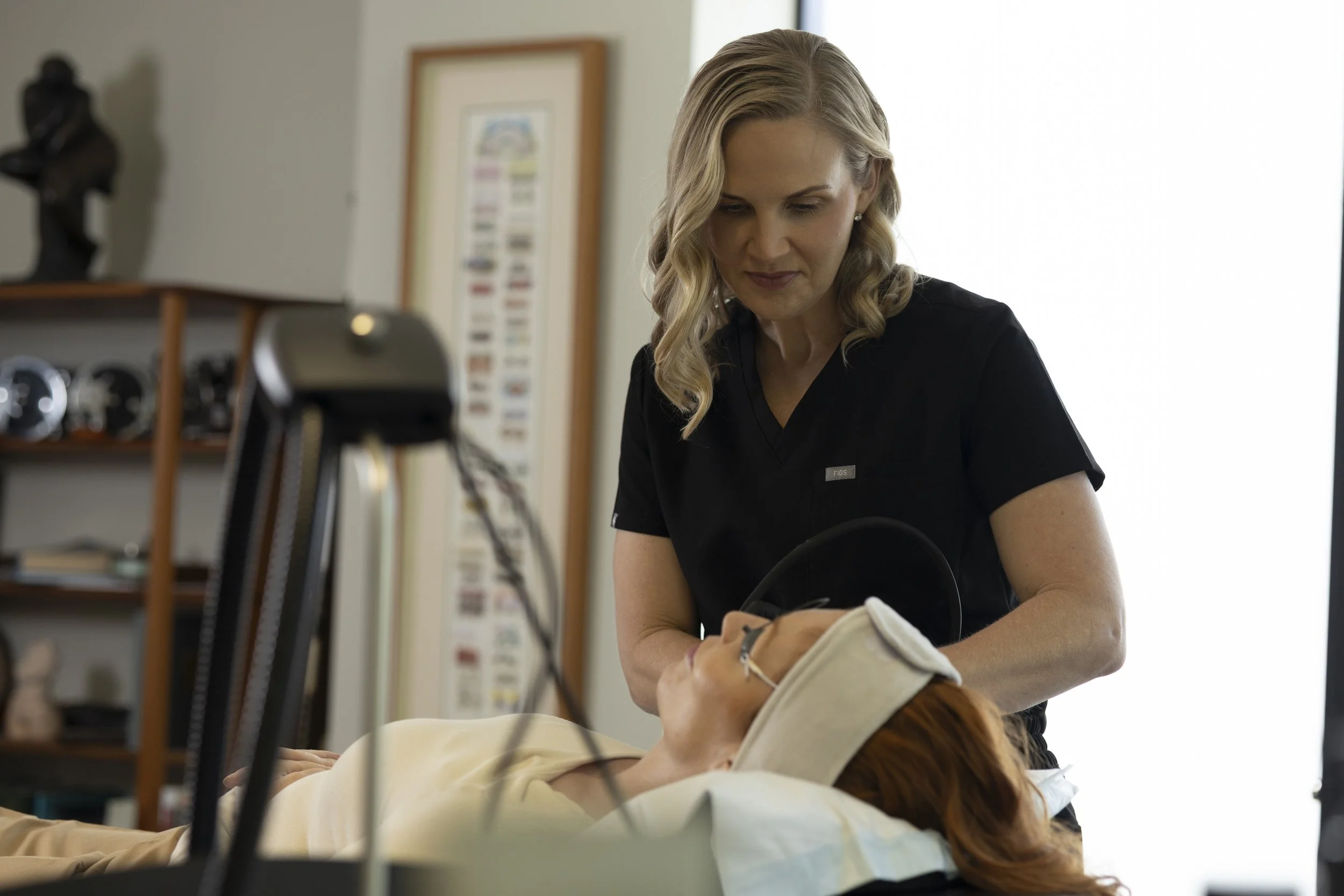A healthcare professional performing a procedure on a patient lying on a medical bed.