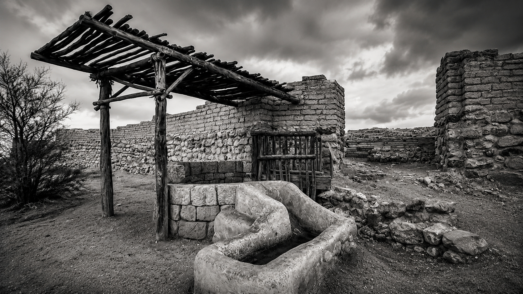Black-and-white reconstruction of an ancient Near Eastern settlement with stone walls, adobe structures, and a water basin, illustrating the landscape of the patriarchal world.
