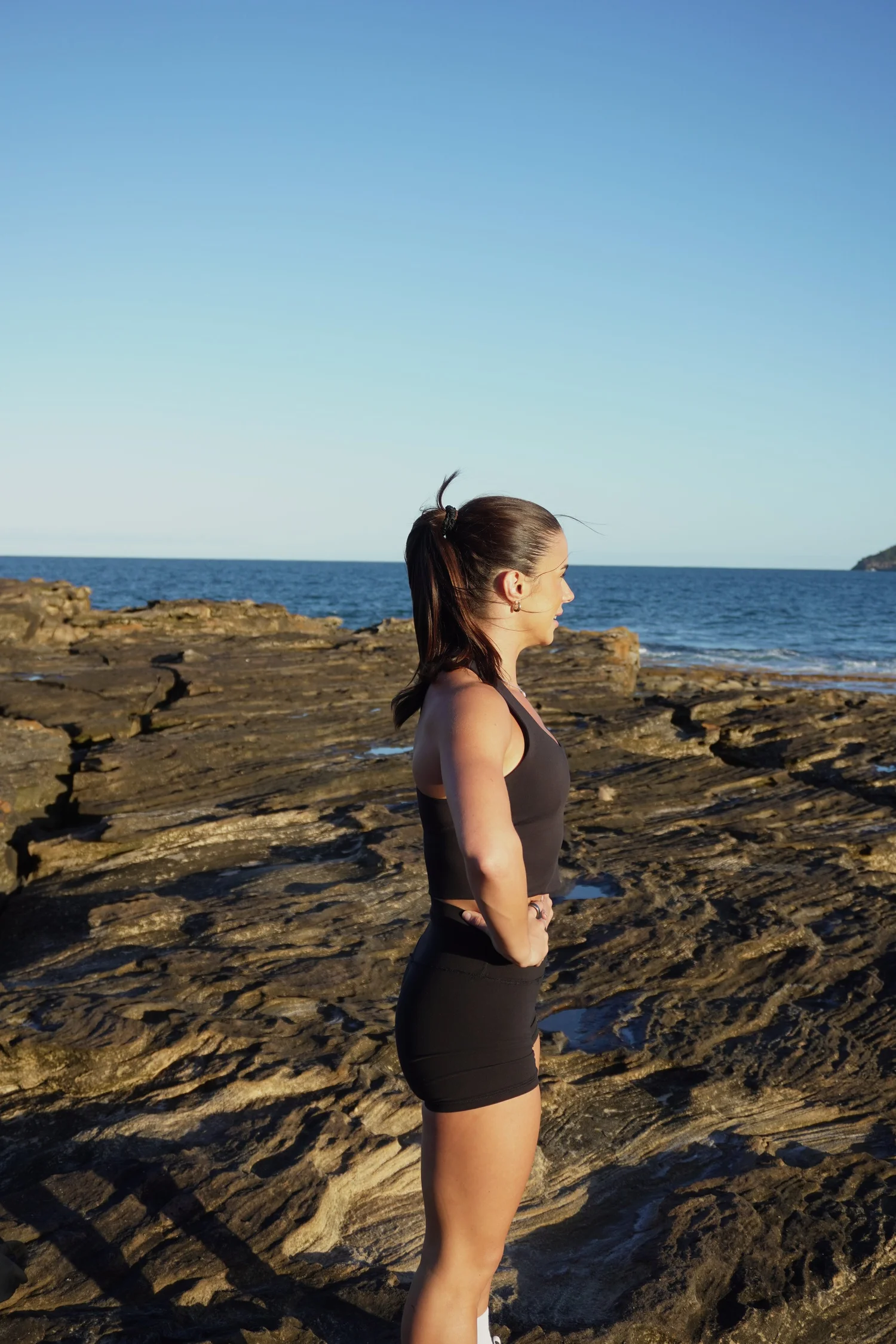 Maddi looking out to the ocean, hands on hips