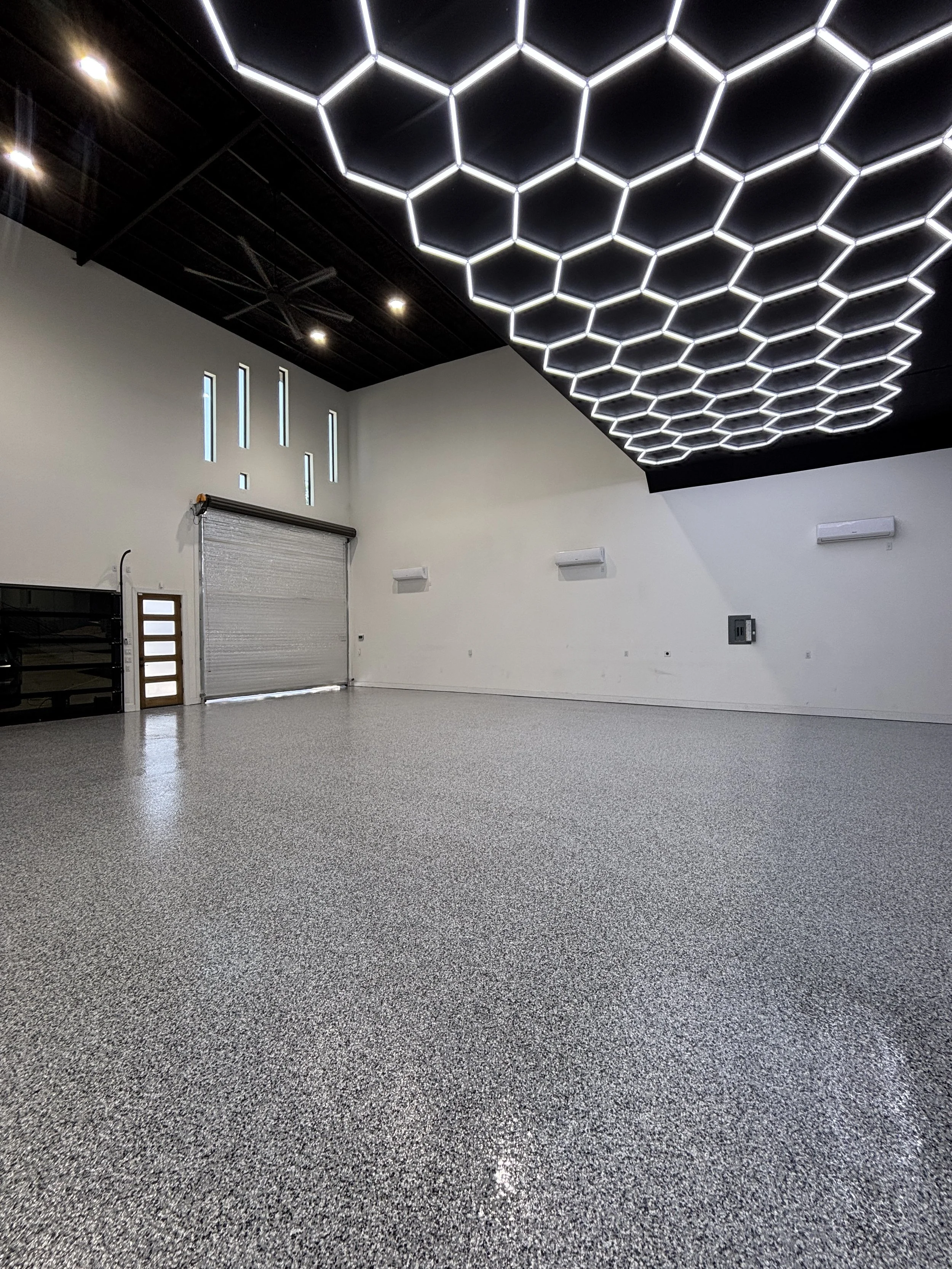 Empty garage with hexagonal LED ceiling lights and high windows.