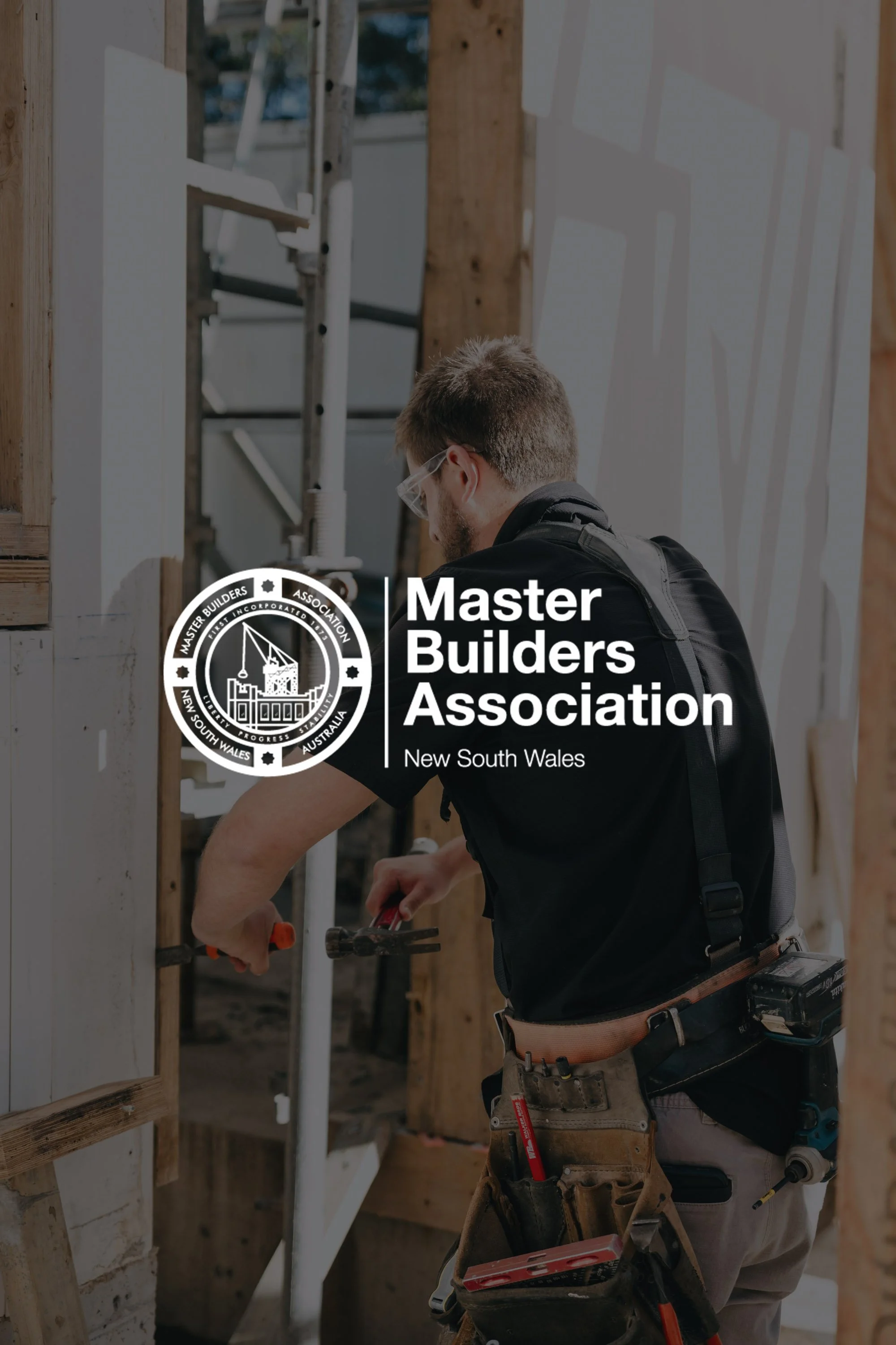 A man working on a construction site, using a hammer. He is wearing safety glasses and a tool belt. Overlay text reads 'Master Builders Association, New South Wales' with a logo.