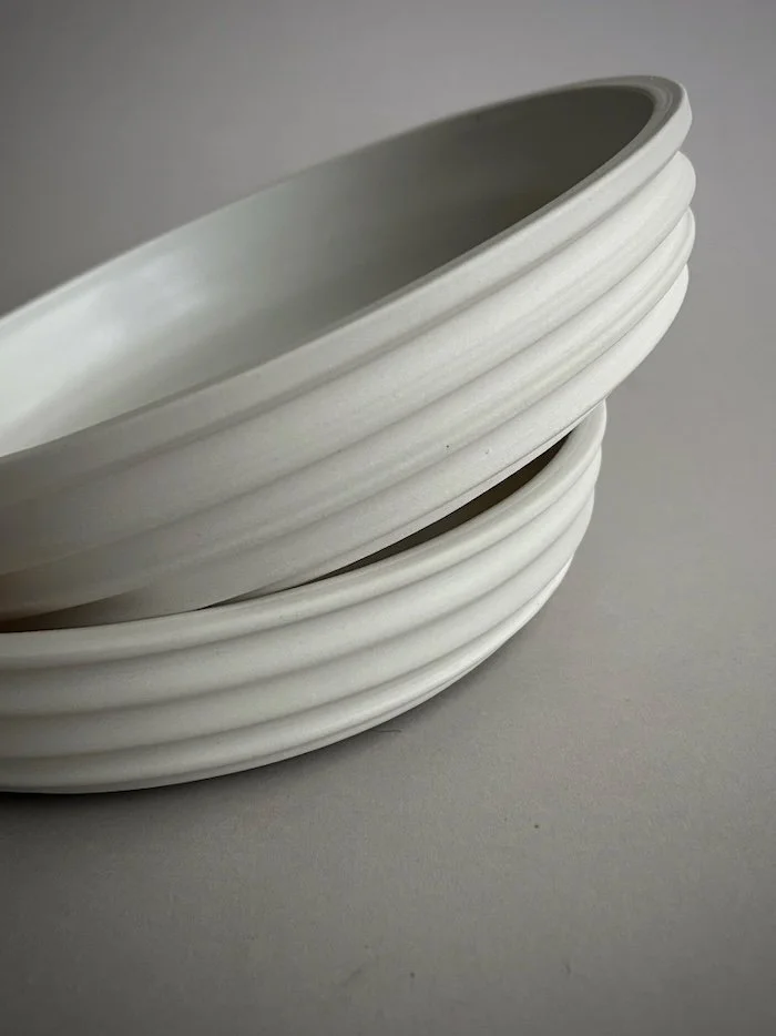 Stacked white ceramic bowls on a gray surface.