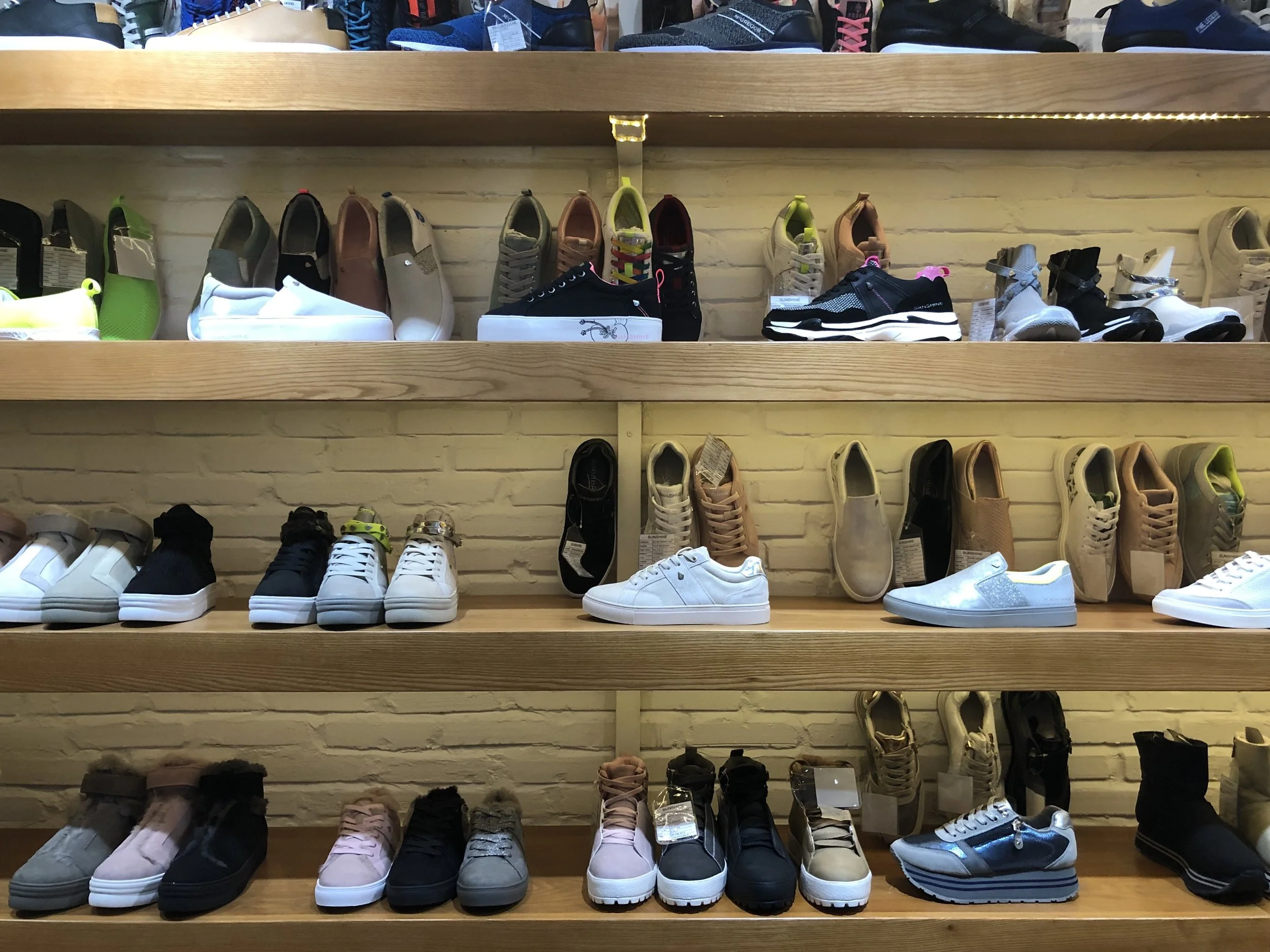 Display of various sneakers on wooden shelves in a shoe store, sample room.