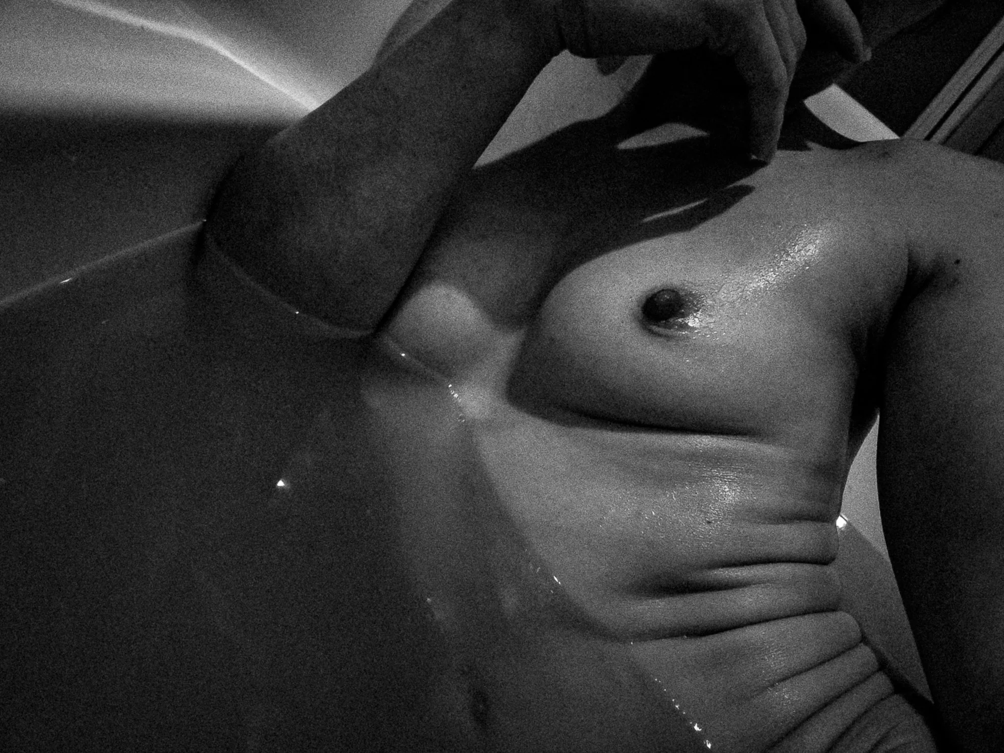 Close-up of a person's torso and arm, with a hand resting near the shoulder, in black and white.