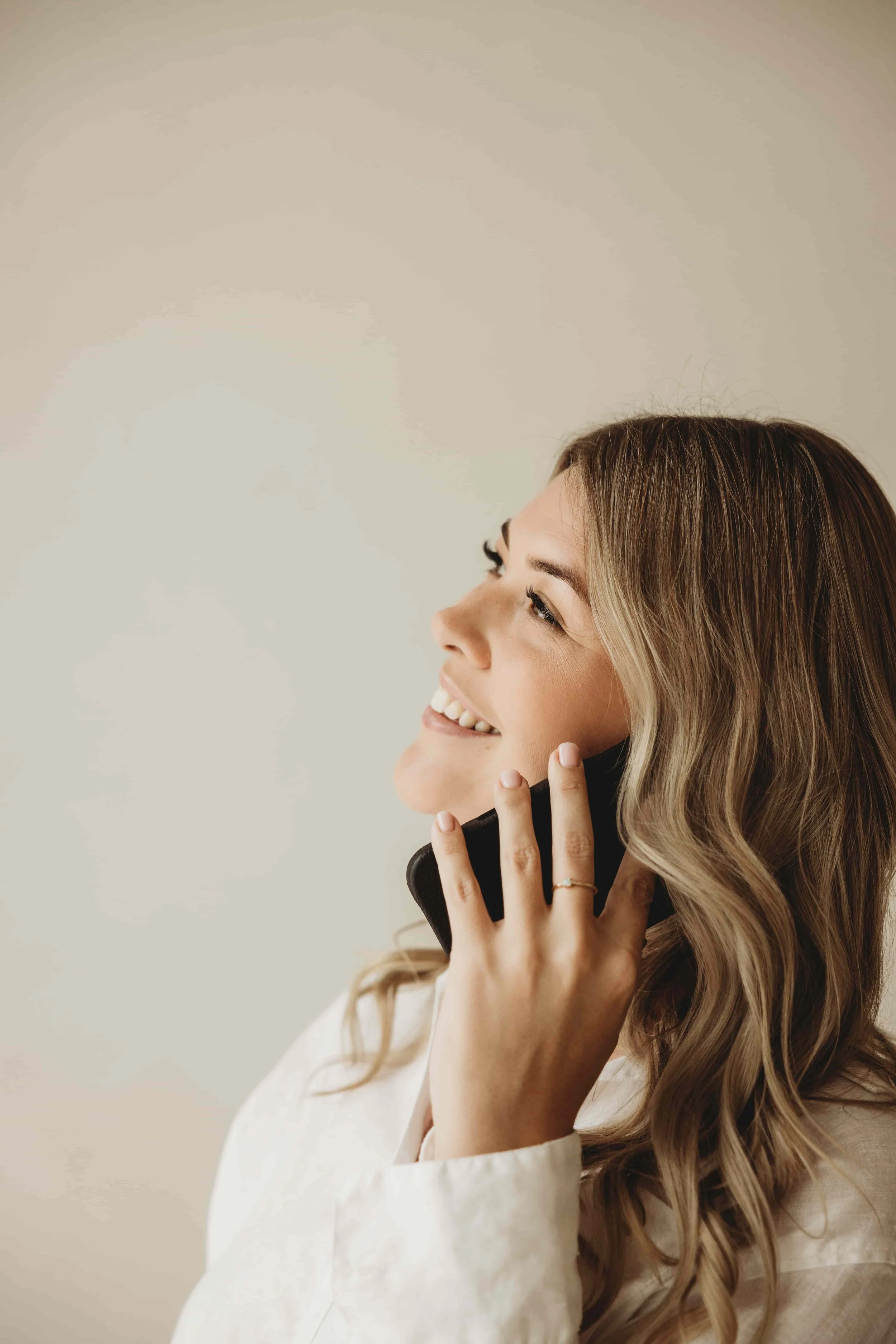 Kiara Jade Trotter with wavy blonde hair, smiling, talking on a cell phone, wearing a white shirt.