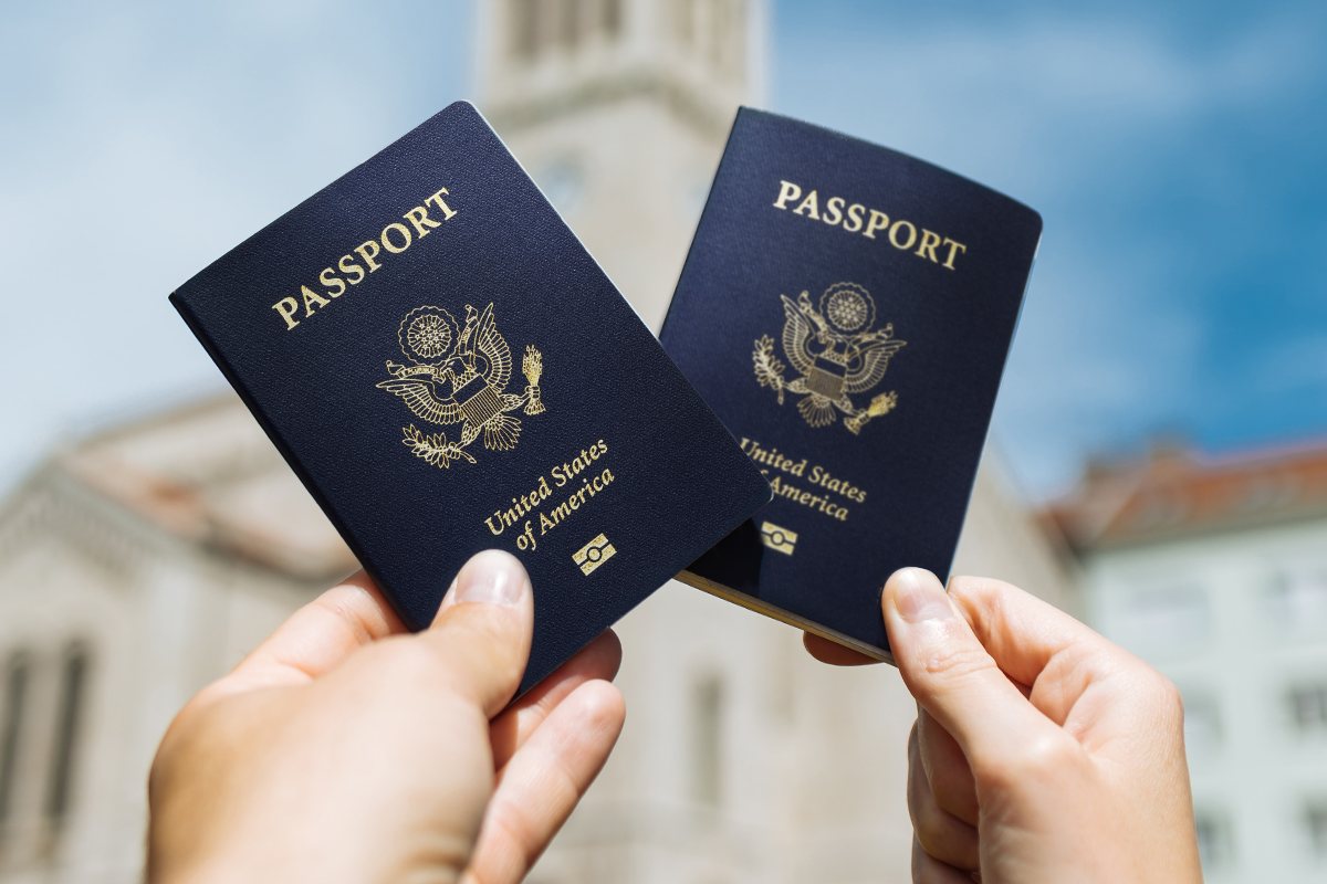 Two hands holding United States passports against a blurred background. Represents successful U.S. immigration outcomes through EB5 real estate investments.