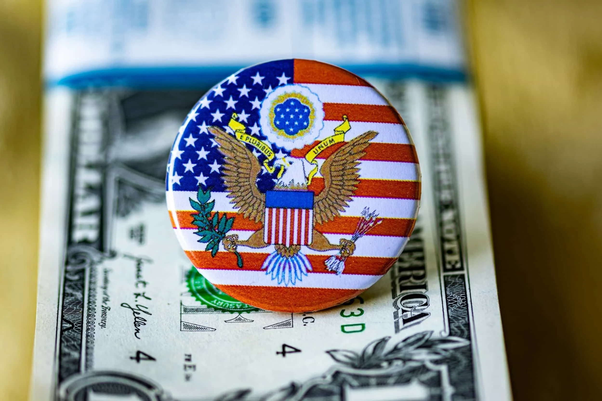 A U.S. emblem button with stars and stripes on a dollar bill, symbolizing EB5 investment and Green Card opportunities through capital investment.