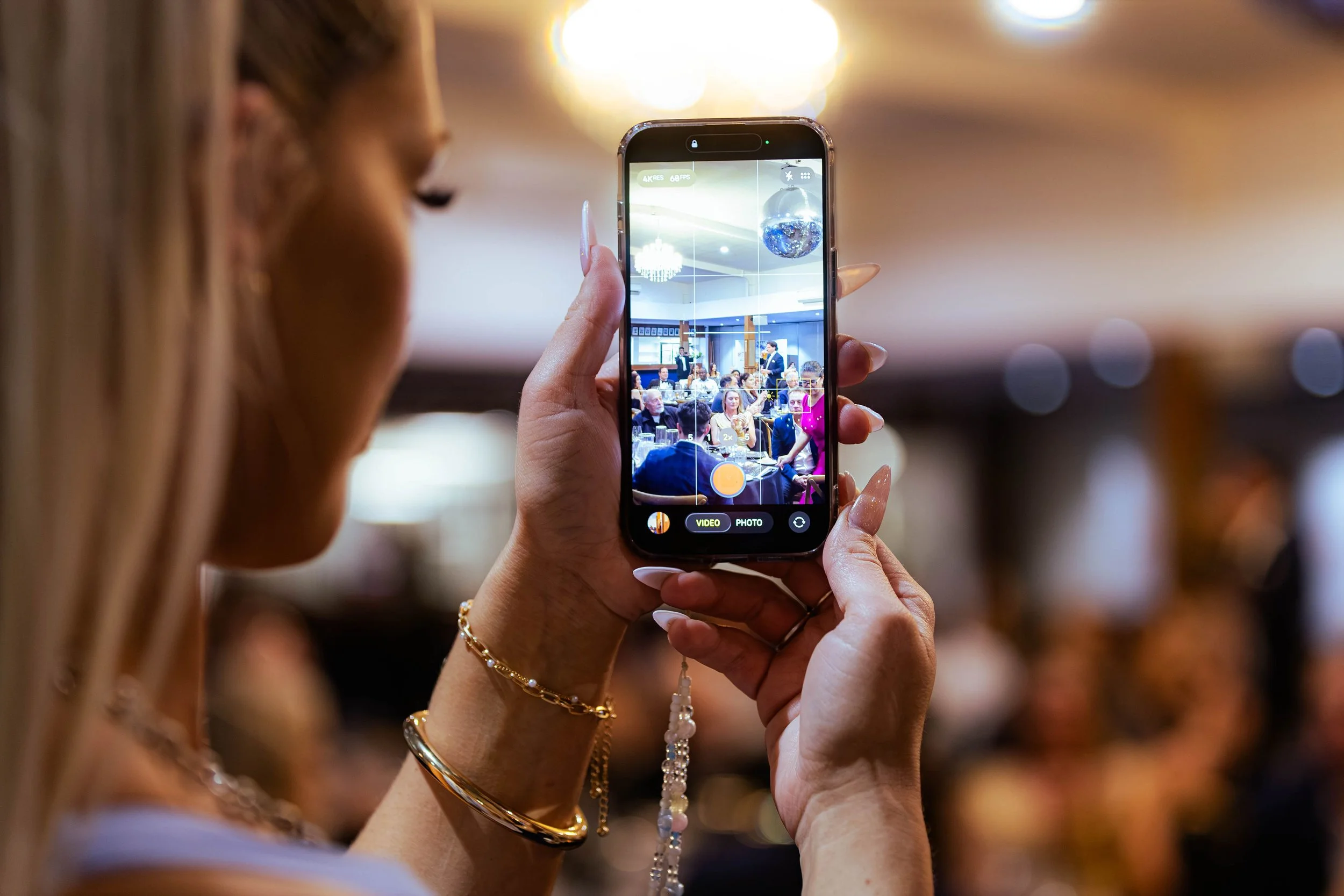 Person taking a photo of a gathering with a smartphone at an event