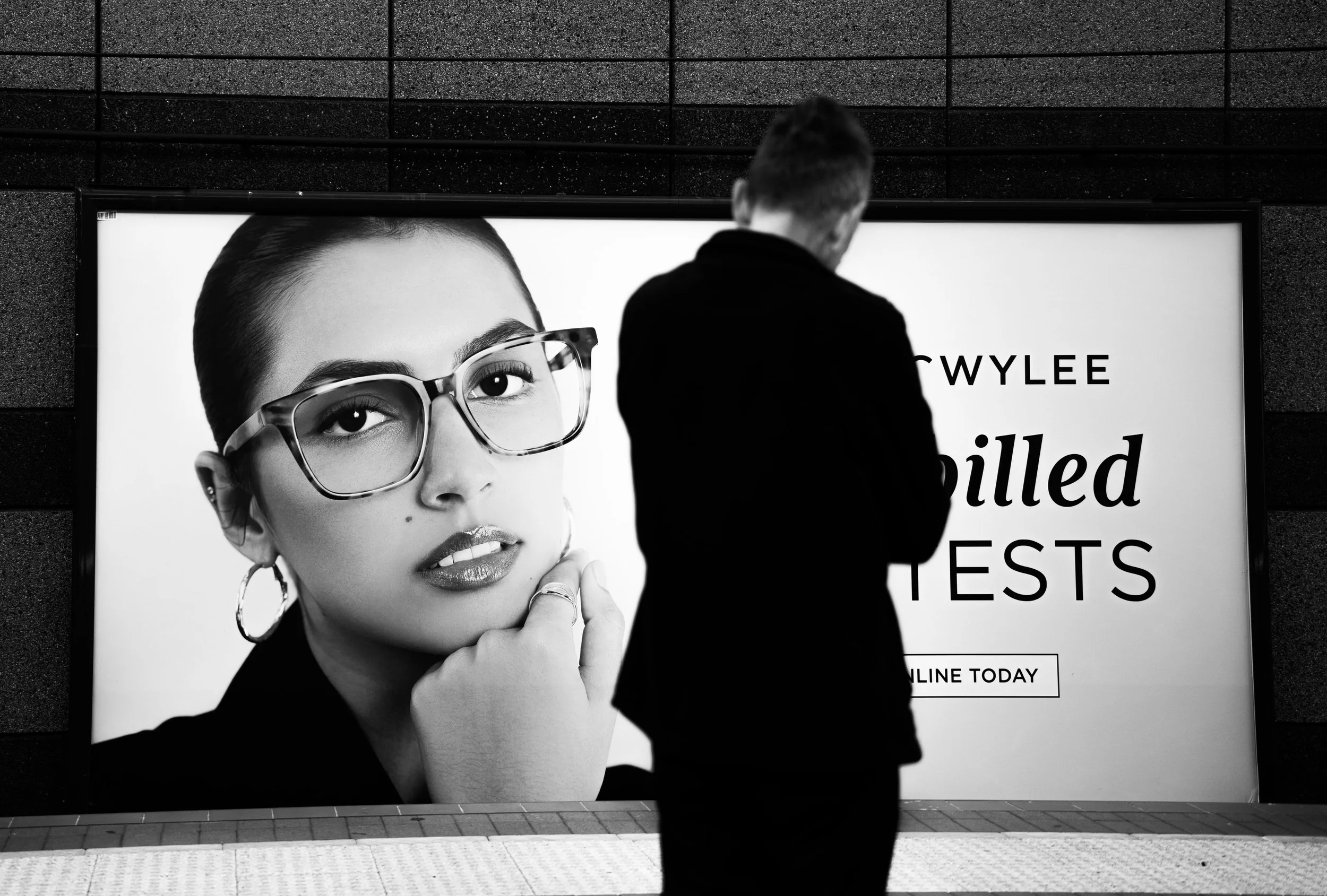 A silhouette of a man in front of an advertisement featuring a woman wearing glasses, with text that reads 'Online Today'.