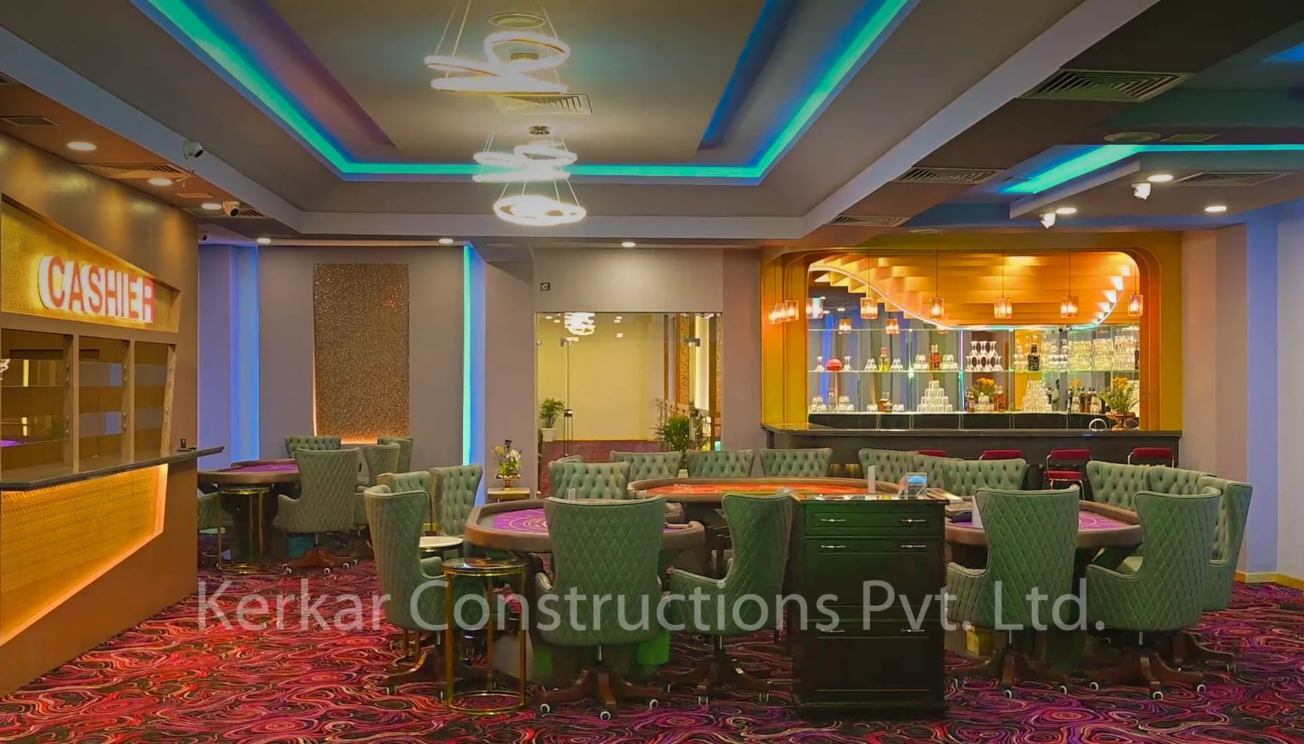 Interior of a casino with playing tables, green chairs, a bar area with glasses and bottles, and colorful ceiling lighting.