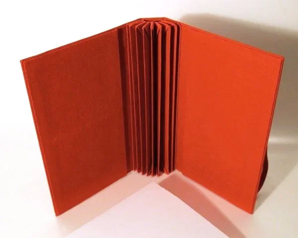 Open red hardcover book with blank pages inside, standing upright on a white surface.