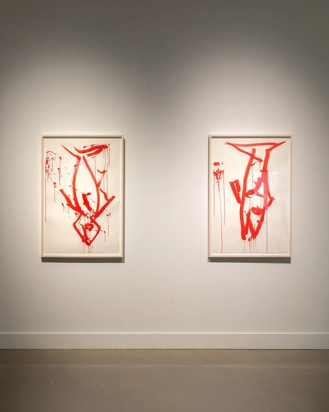 Two gestural works on paper by Joan Jonas with red brushstrokes on white backgrounds, displayed side by side in a museum with white walls and concrete floors.