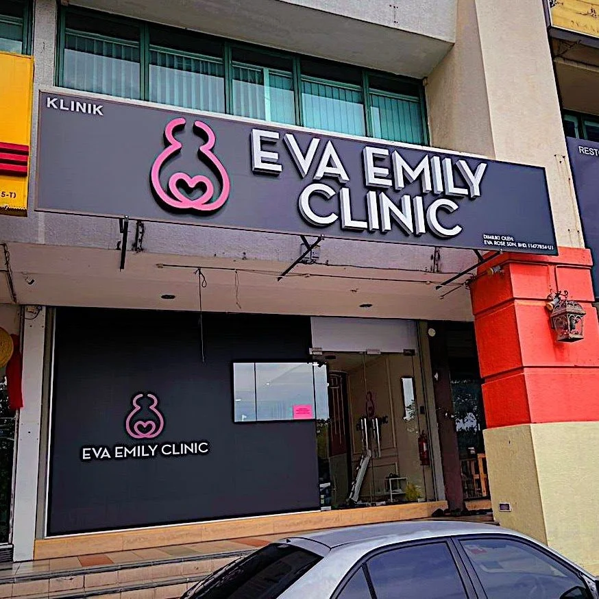 Sign on building for Eva Emily Clinic with pink logo of a stylized baby and the clinic's name in bold white and purple letters.