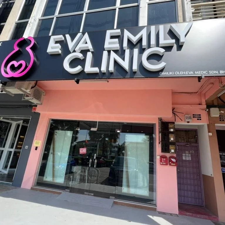 Exterior of Eva Emily Clinic with pink and black signage, glass entrance door, and pink-painted wall.