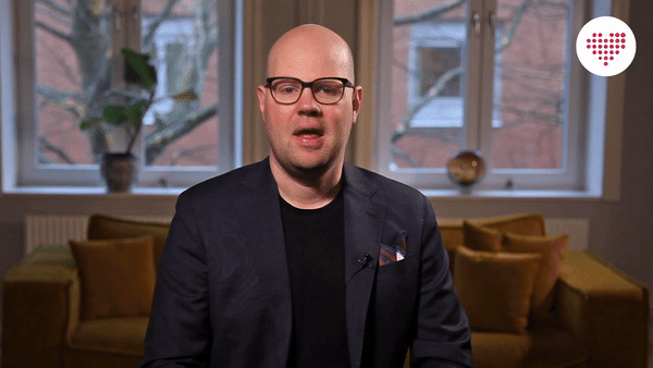 Tobias Sturesson sitting in a living room with yellow cushions and large windows.
