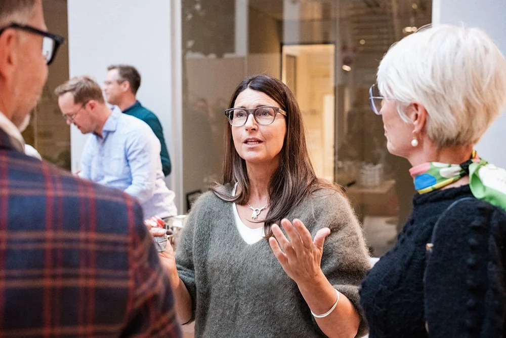 Women having a conversation at a Heart Management event, with other people in the background.
