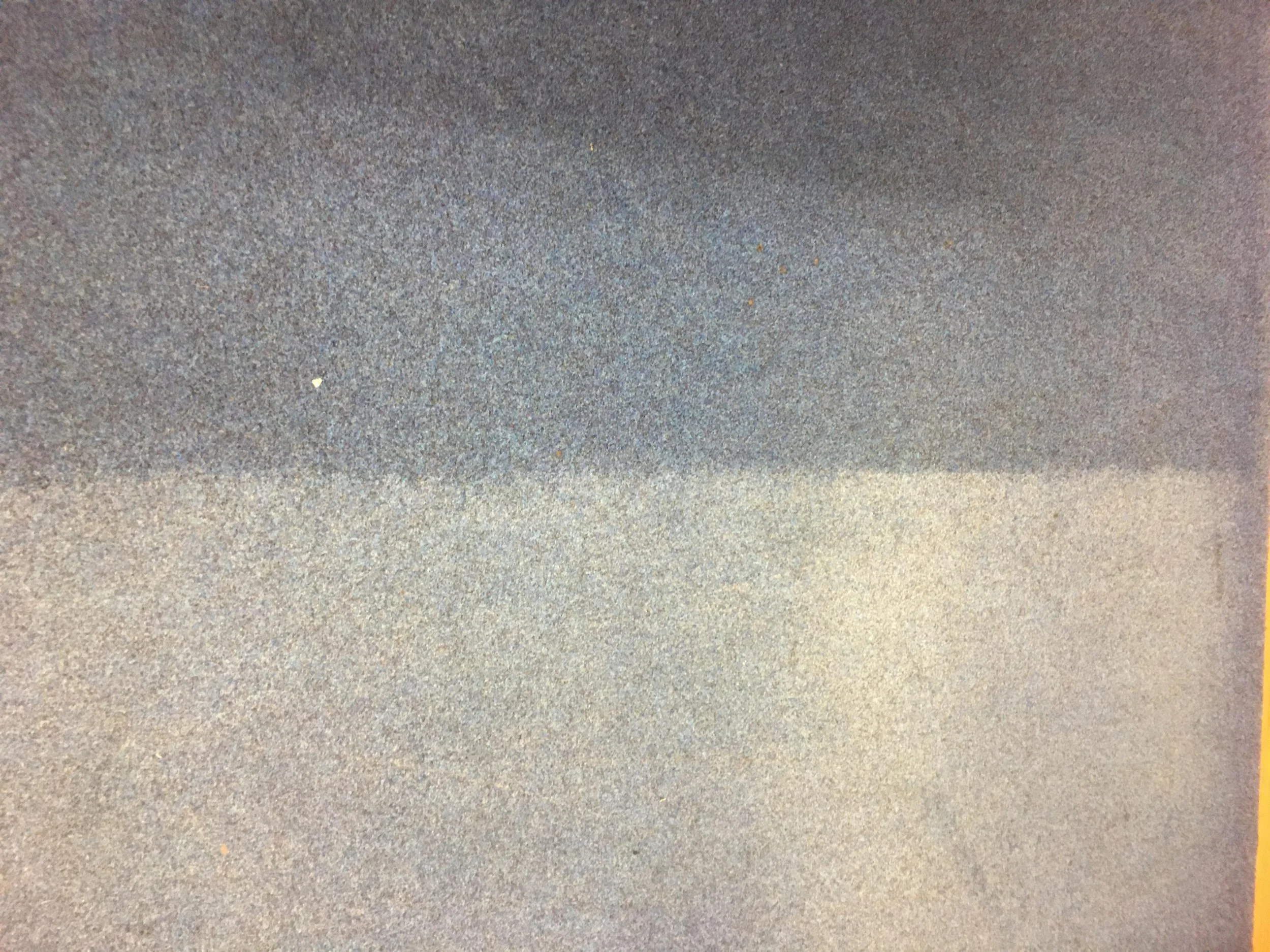 A close-up view of a textured metal surface with a gradient of colors from dark gray to light gray.