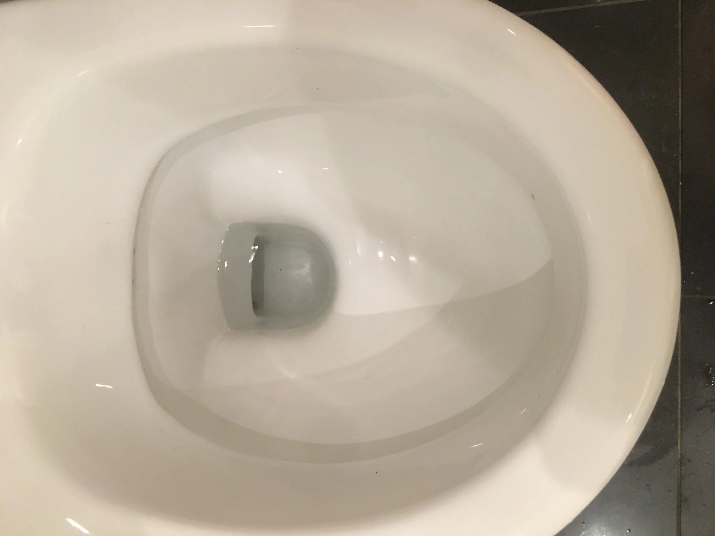 Top-down view of a clean white toilet bowl with water inside.