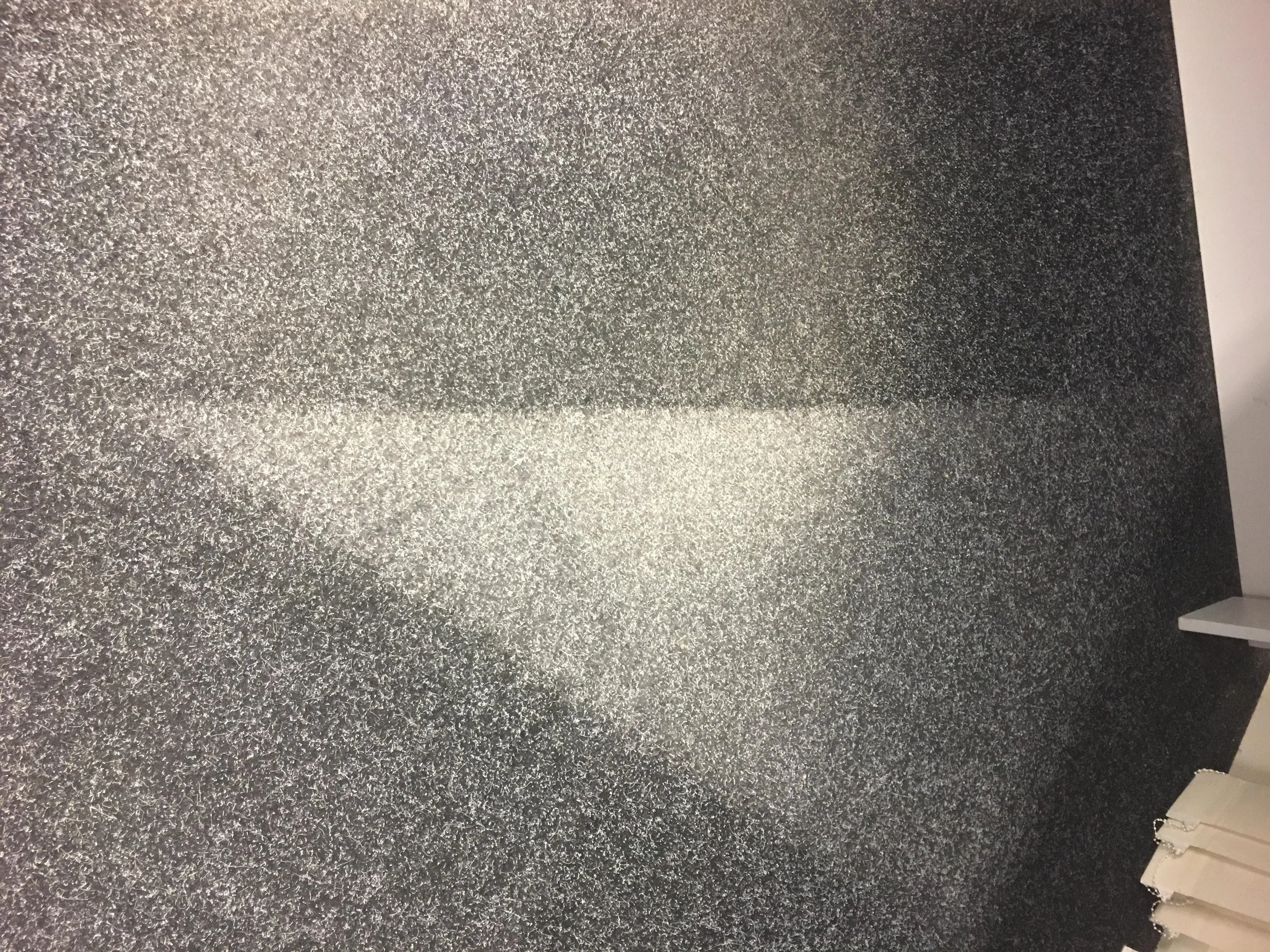 Black speckled tabletop surface with a white rectangular patch of light reflecting on it.