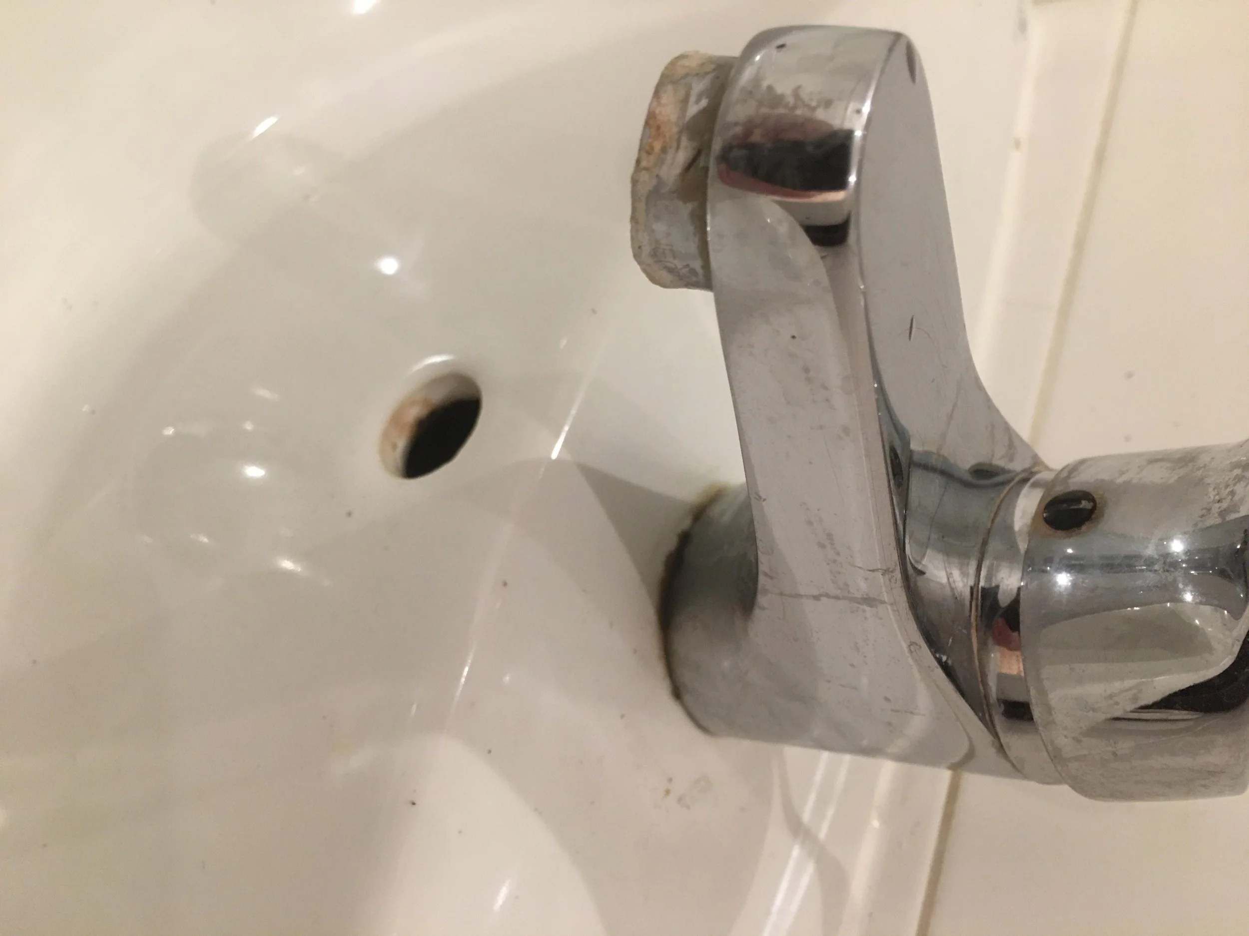 A close-up of a bathtub faucet with visible rust and grime.