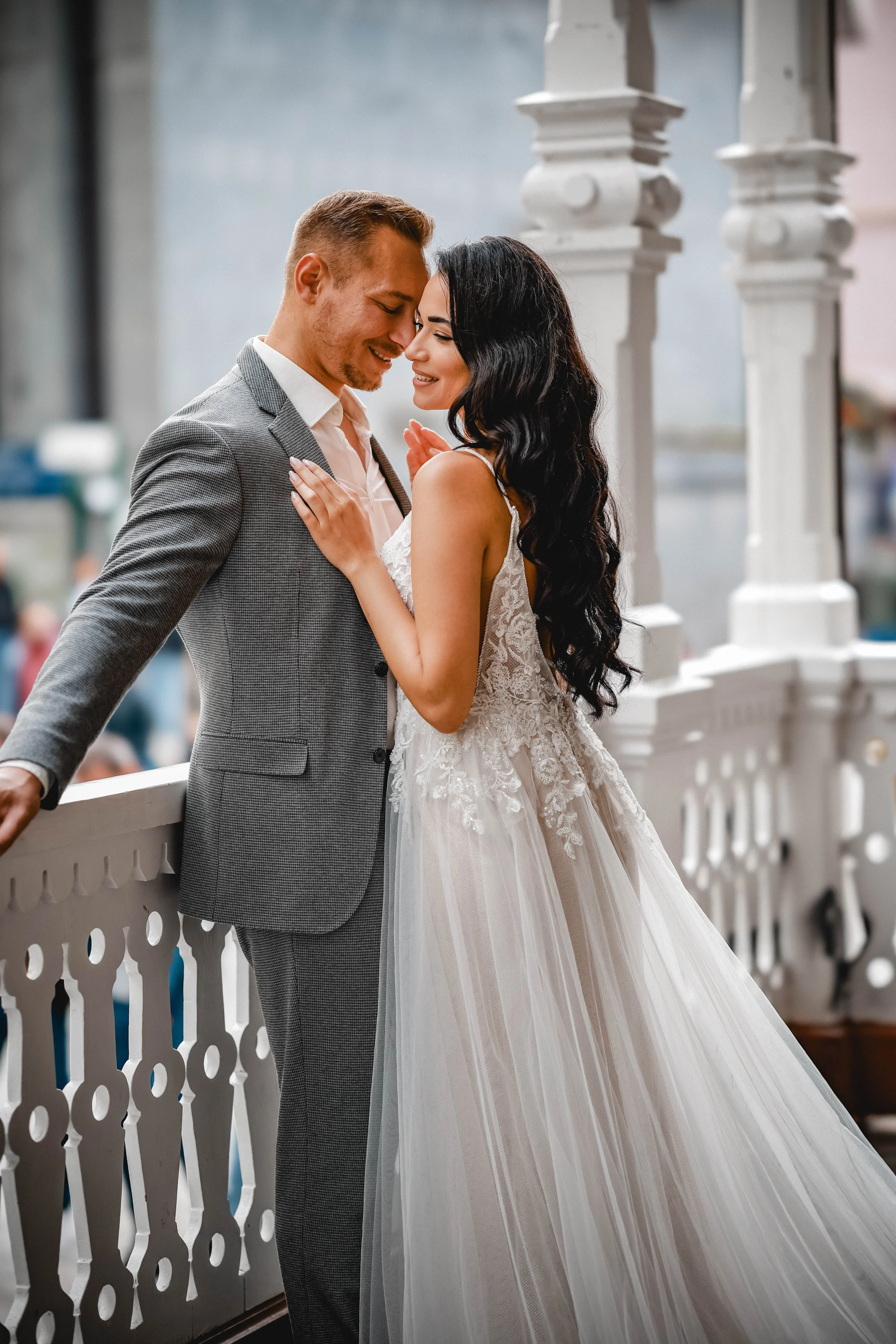 Ein Brautpaar, das auf einer Veranda steht und sich liebevoll zu nuptialen Hochzeitserinnerungen nickt, während sie sich umarmen.