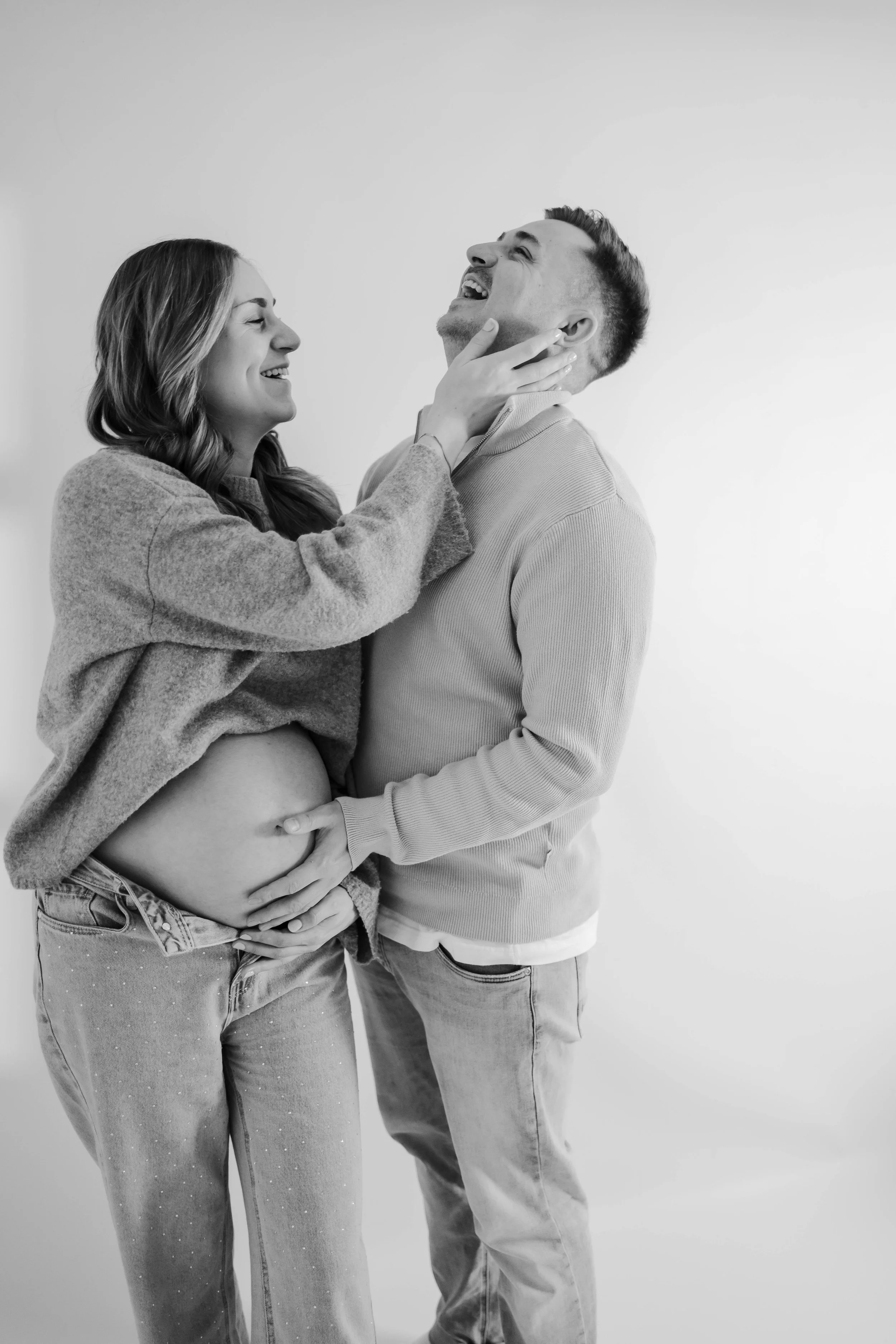 Ein glückliches Paar, das gemeinsam ein Baby erwartet, zeigt Freude und Zuneigung, wobei die Frau das Babybauch hält und bisher ungeboren ist.