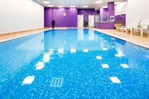 Indoor swimming pool with purple walls and white lounge chairs