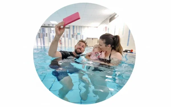 A man, woman, and child taking a selfie in a swimming pool.