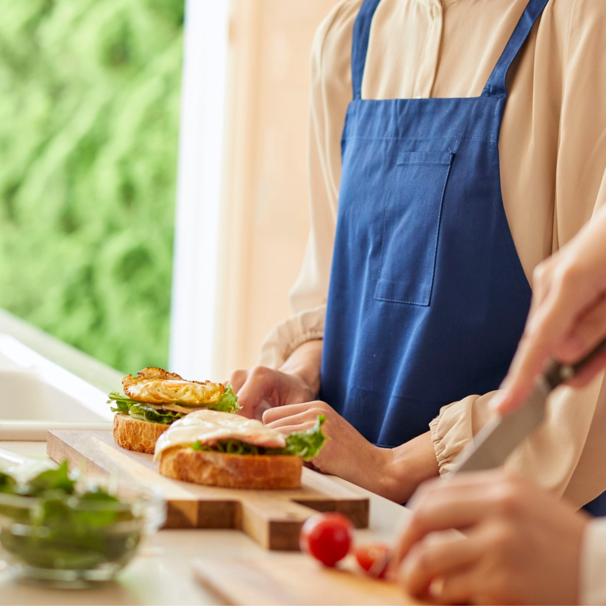 Menschen bereiten Sandwiches mit frischen Zutaten in einer Küche vor.