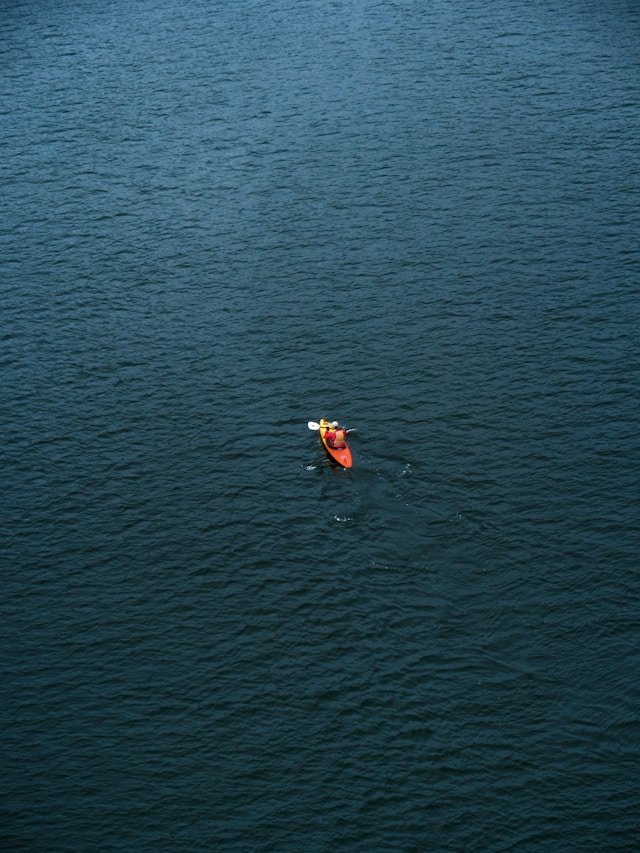 Vue aérienne d'une personne seule en canoe sur la mer — l'impression parfois de ramer