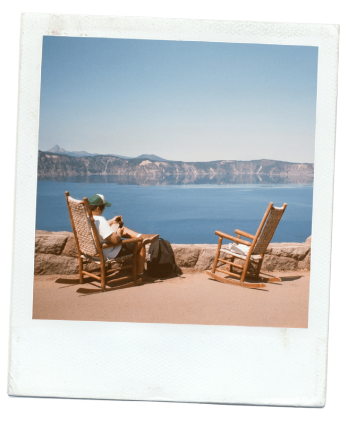 Polaroid — personne assise dans un rocking chair face à un lac et des montagnes, avec un autre rocking chair vide à côté