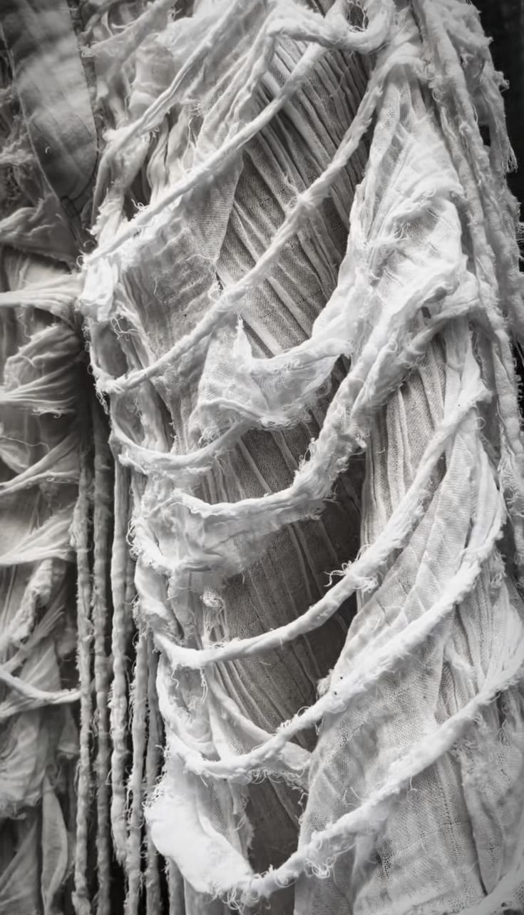 Close-up of torn, tattered fabric or cloth with frayed edges and holes, appearing worn and distressed.