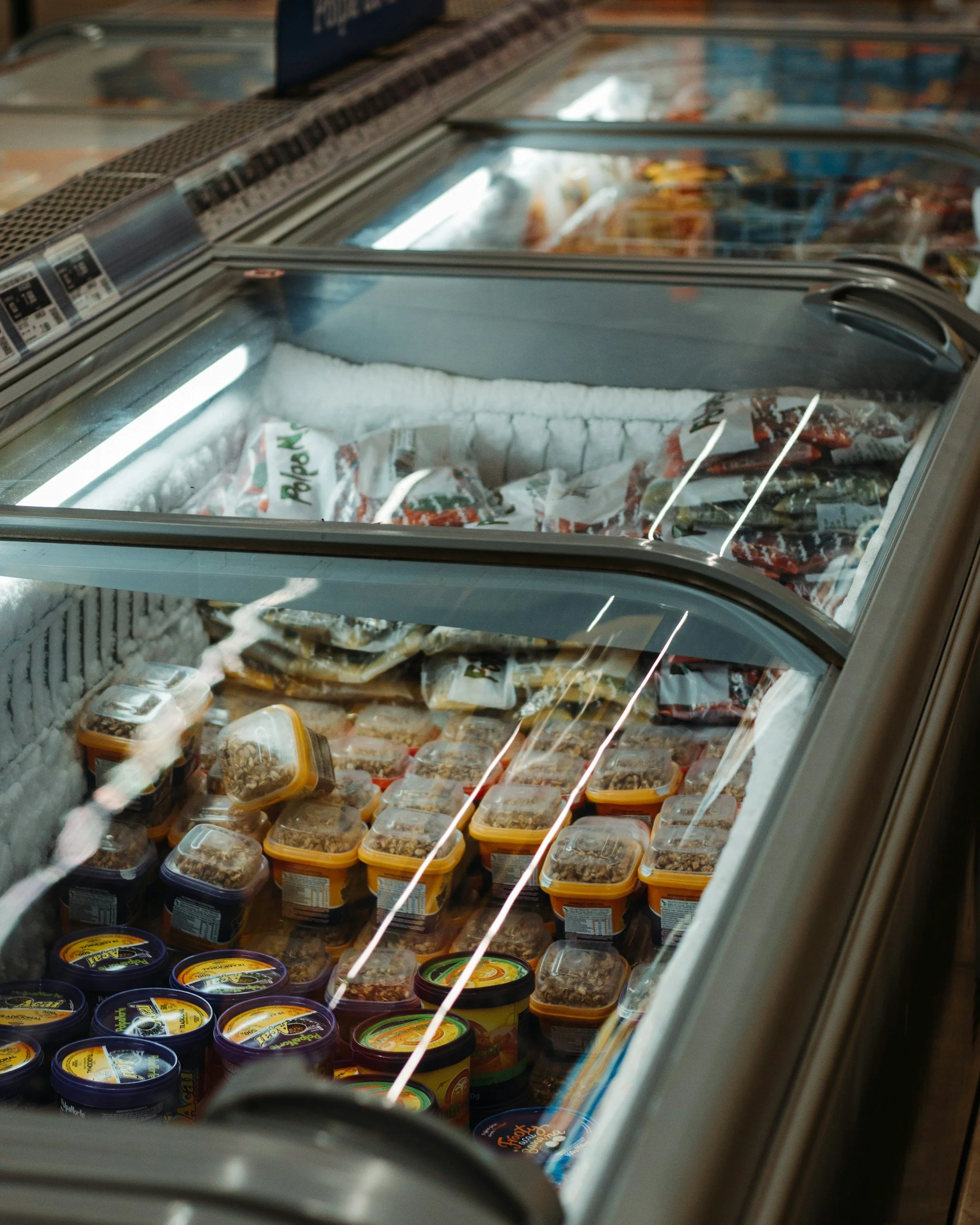 Frosted freezer with various packaged frozen foods and tubs of ice cream.