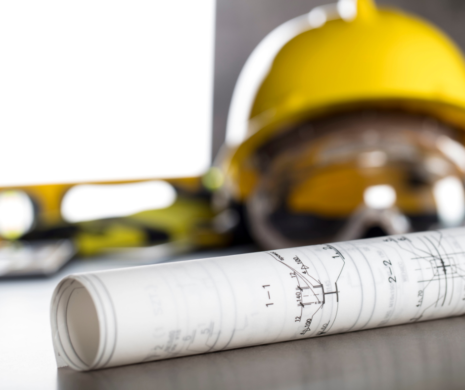 Rolled architectural blueprint and yellow safety helmet on a flat surface.