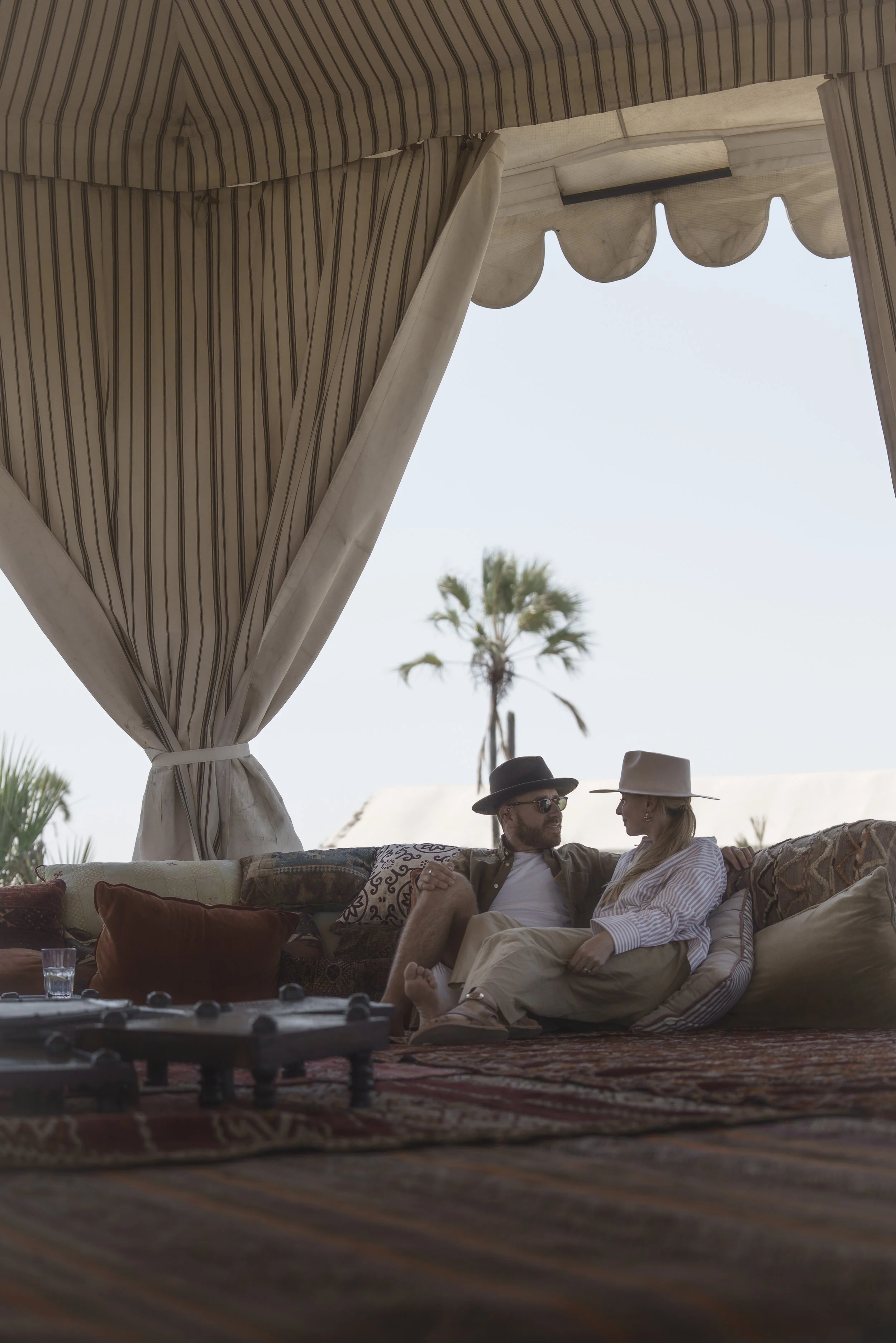Couple relaxing on cushions under a canopy at a safari lodge