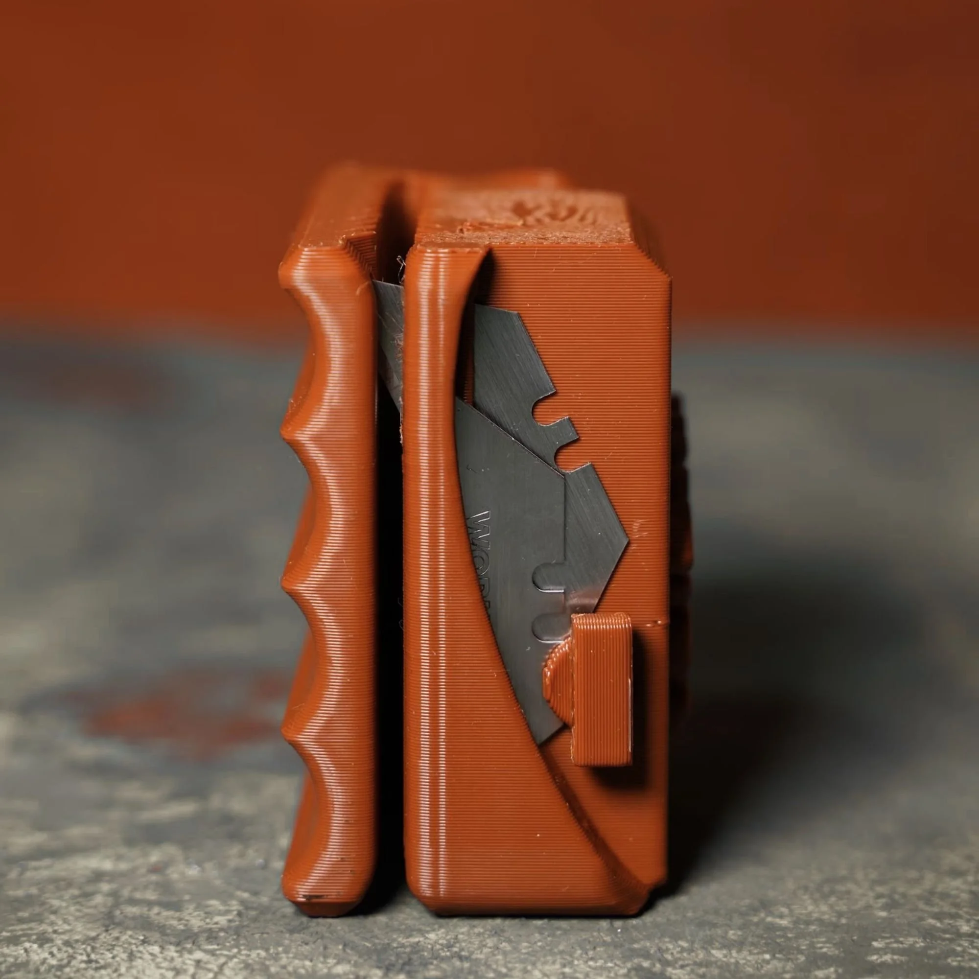 Close-up of orange plastic fins on a heatsink, with a gray metallic base visible at the bottom, placed on a concrete surface.