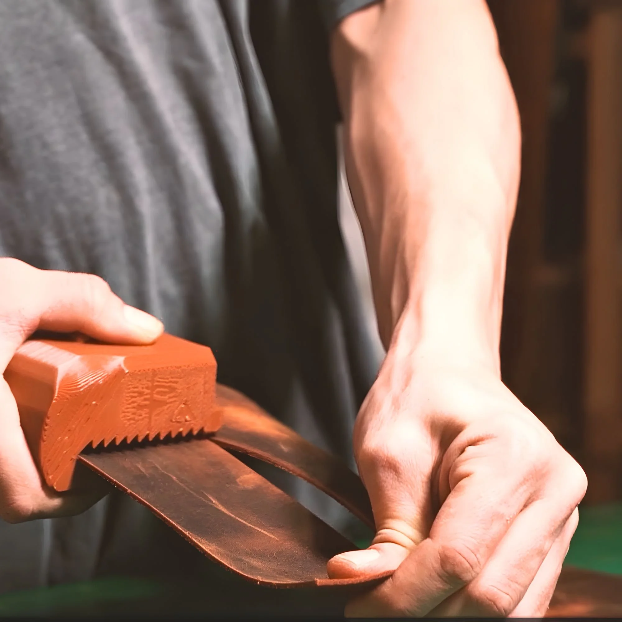 Close-up of a person's hand holding a wooden-handled saw, cutting through a piece of wood.