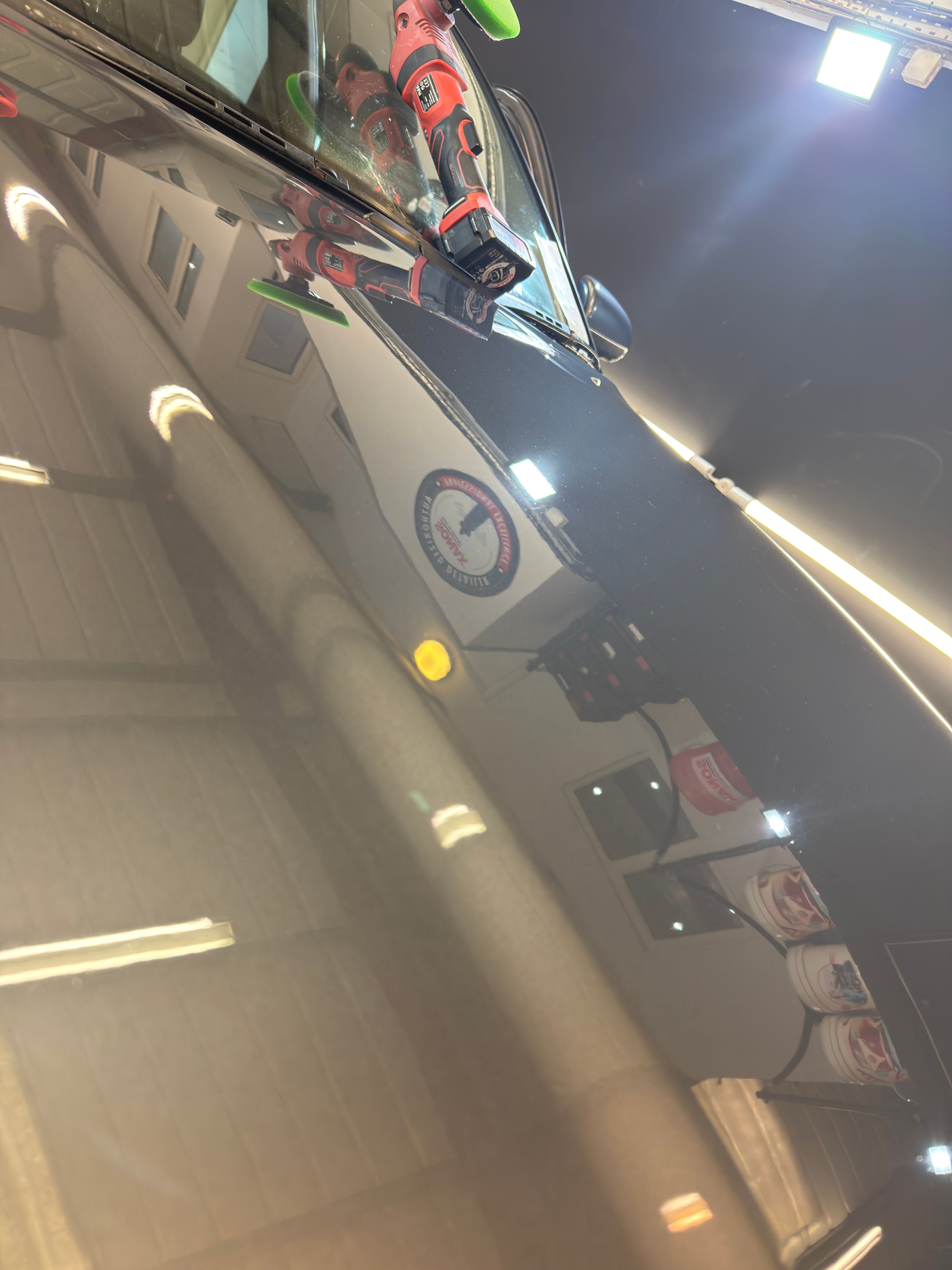 Reflection of a truck with a logo, power tools, and indoor lighting in a shiny surface.