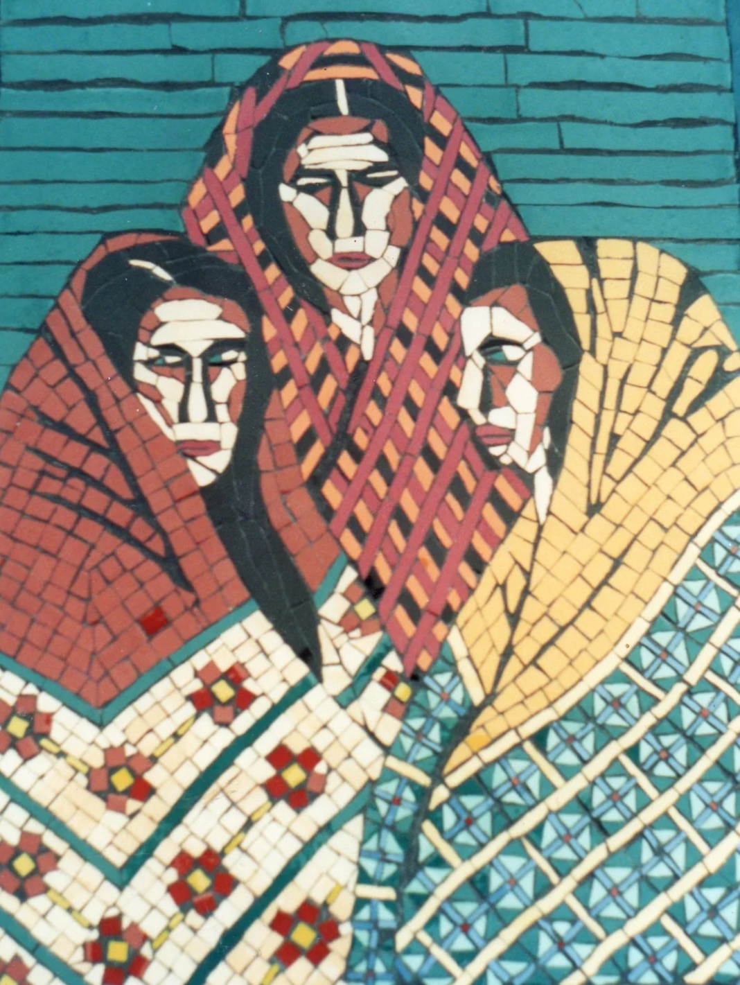 Three women standing together, wearing brightly coloured shawls on a teal background