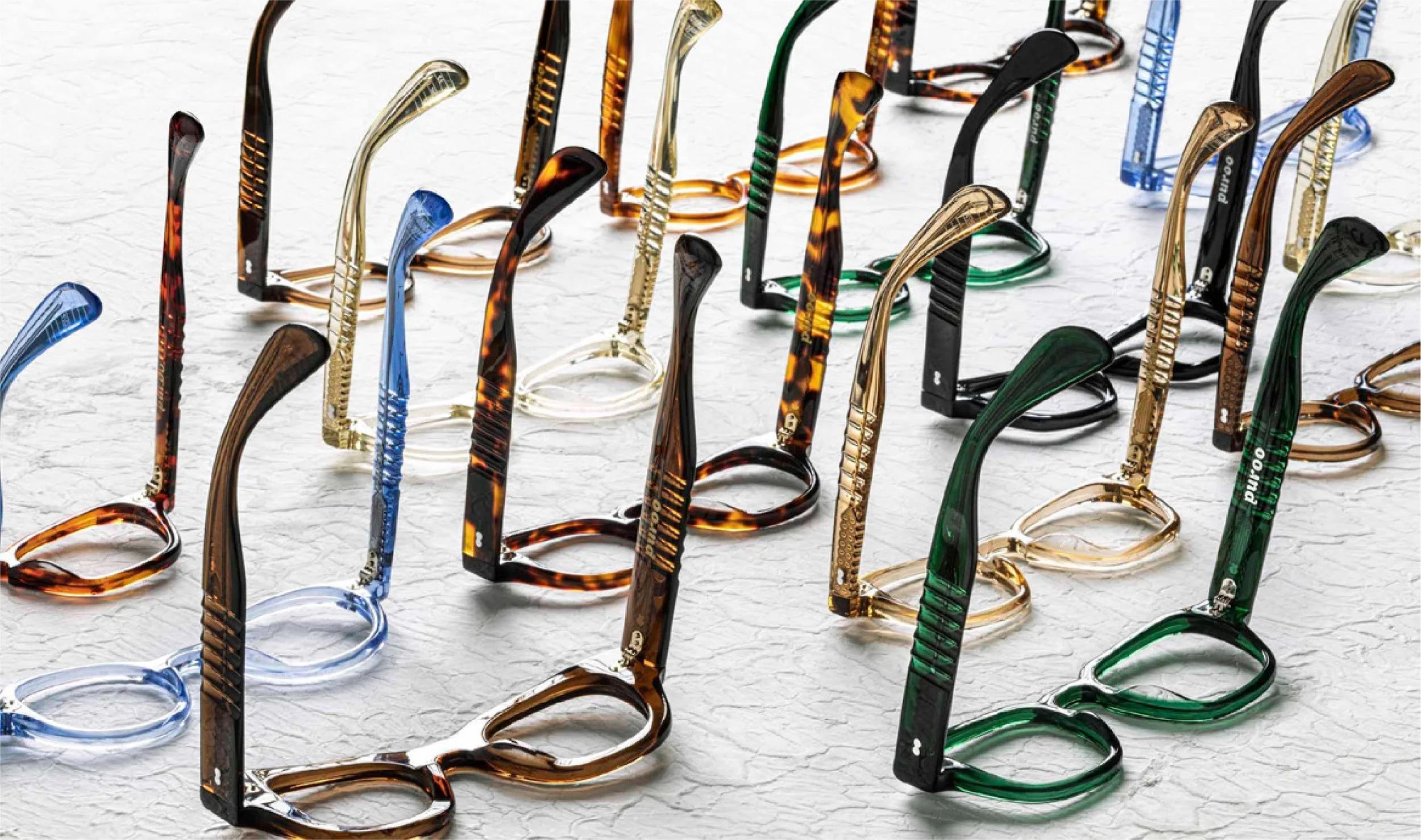 A collection of eyeglasses with colorful tortoiseshell and black frames, arranged on a white textured surface.